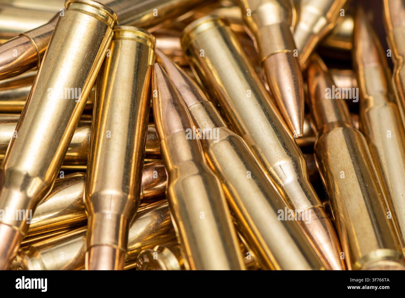 Eine Nahaufnahme zeigt einen Stapel metallischer Gewehrpatronen, die in einem engen Bildrahmen überlappen. Stockfoto