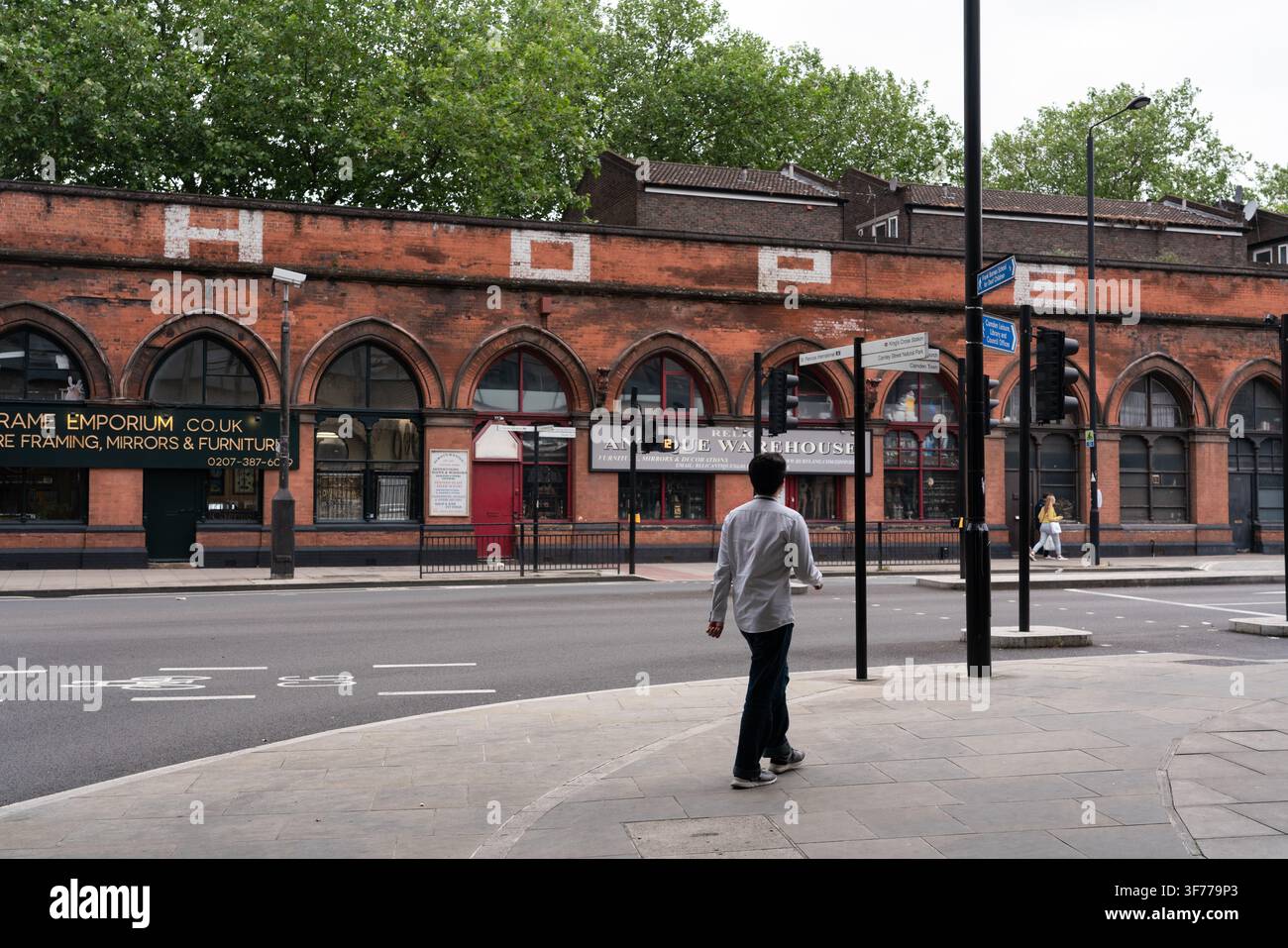 Ein Fußgänger geht die Pancras Road in Camden, London, vorbei am ikonischen Relic Antique Warehouse und seinem berühmten "HOPE"-Ziegelbogen. Stockfoto