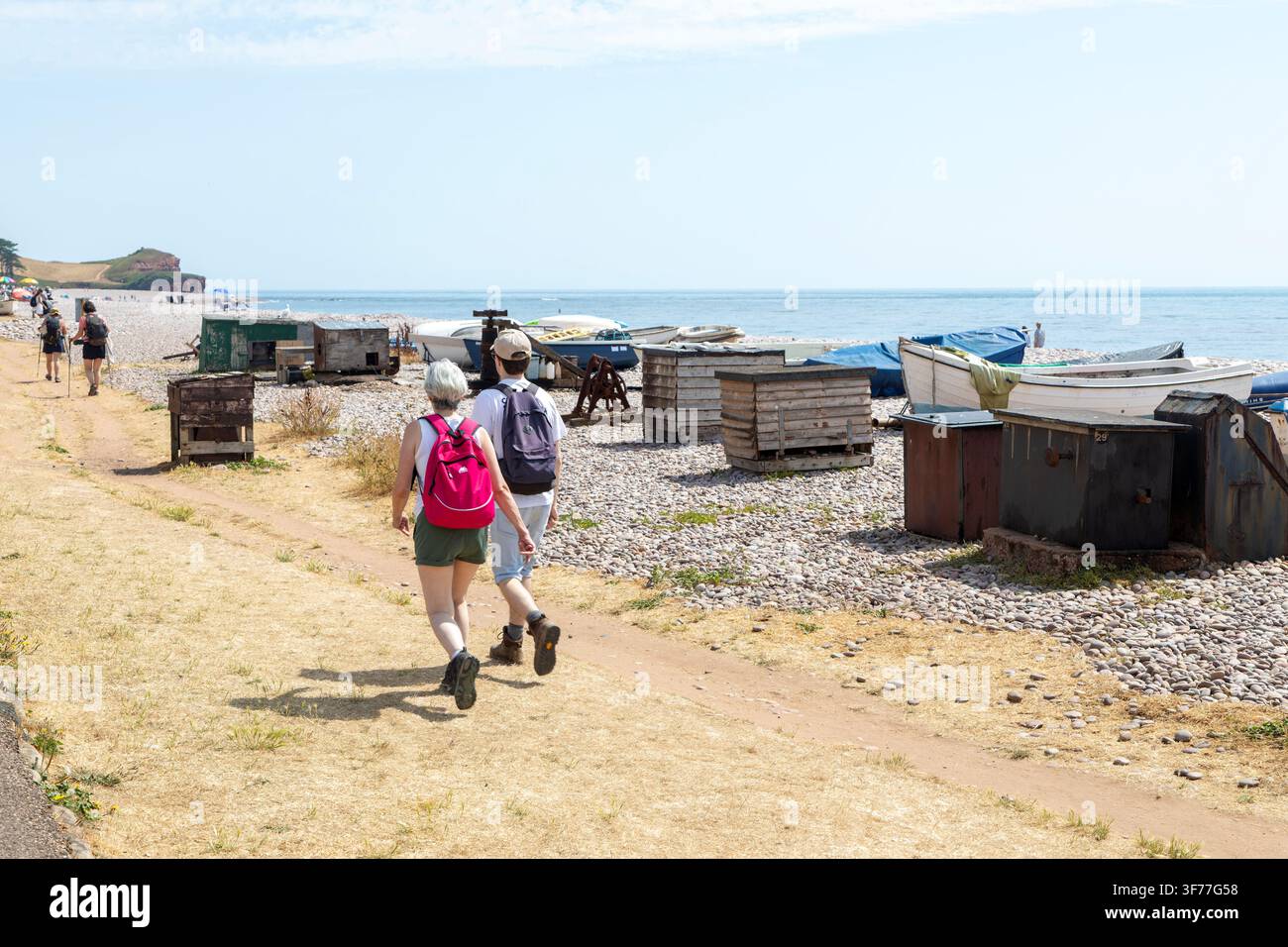 Menschen gehen auf dem Uferpromenadeweg, Boote am Strand, Budleigh Salterton, Devon, England, UK Stockfoto