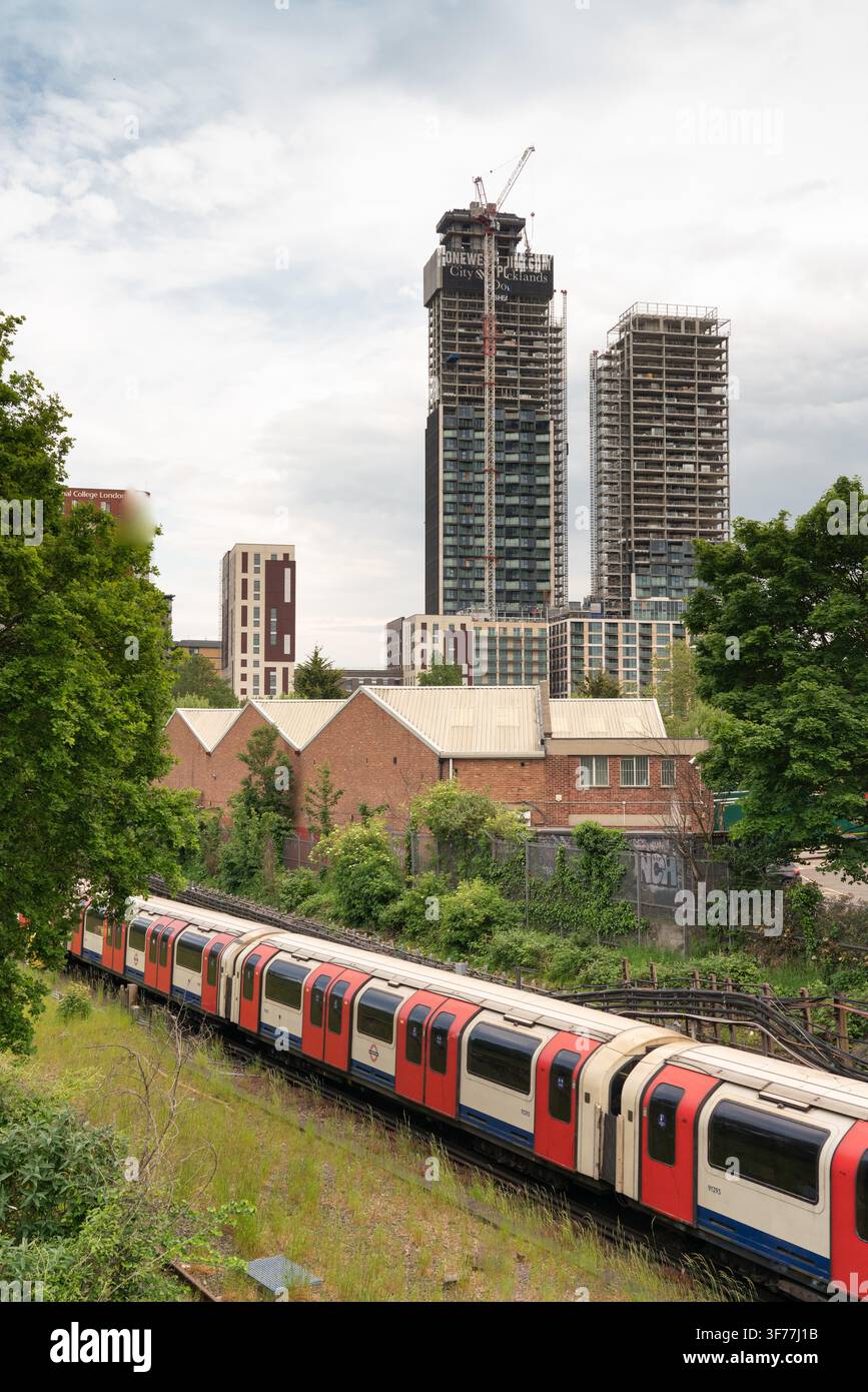 Ein Zug der London Underground Piccadilly-Linie passiert die im Bau befindliche One West Point-Entwicklung in Park Royal, Nordlondon. Stockfoto