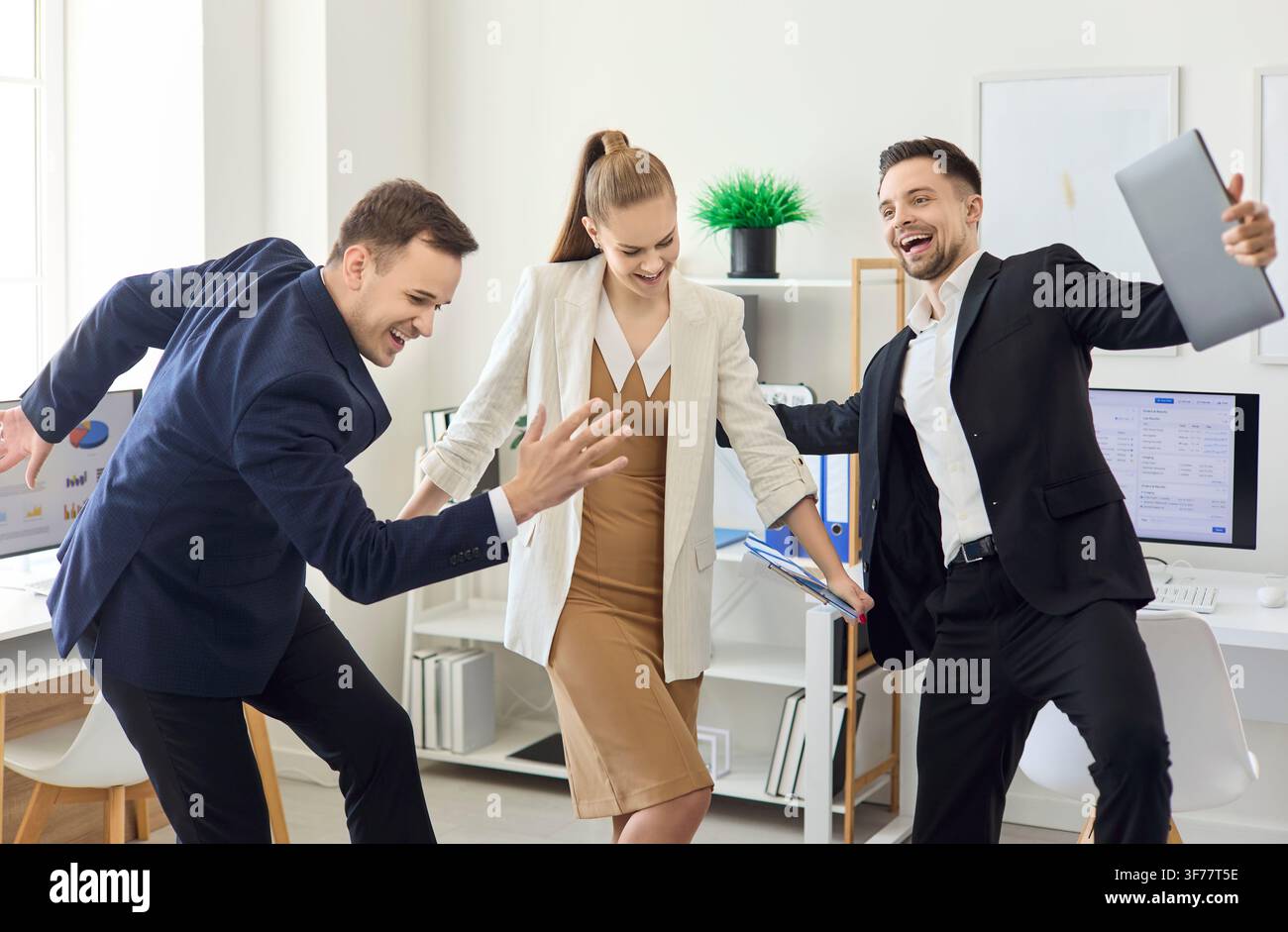 Fröhliche Kollegen tanzen im modernen Büro nach einem Erfolg, Feier des Business-Teams Stockfoto