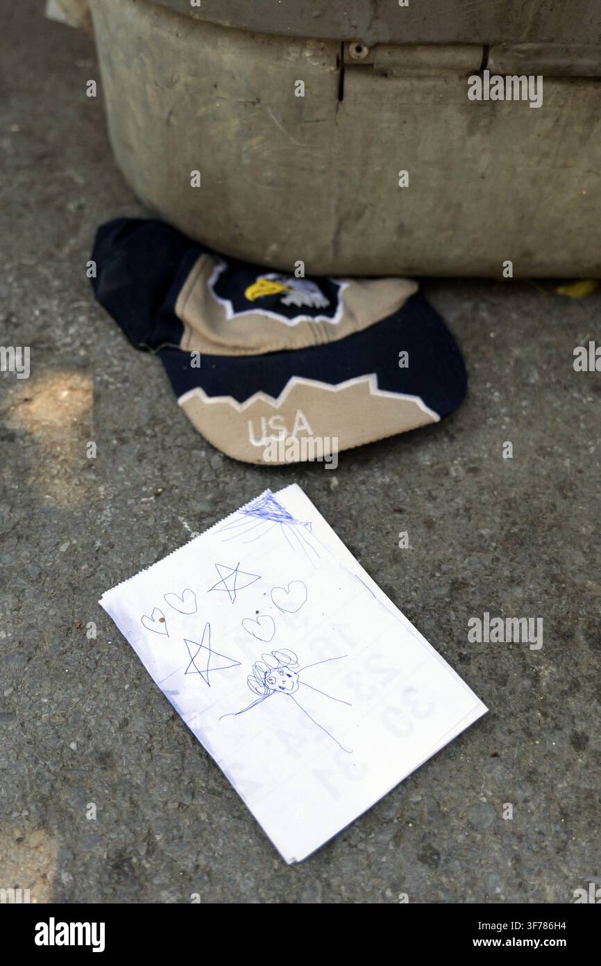 Zeichnung mit Herzen und Sternen auf Papier neben einer Baseballkappe mit amerikanischer Flagge, die kindliche Unschuld und Kämpfe repräsentiert. Bulgarien, Warna, 8. August 2026 Stockfoto