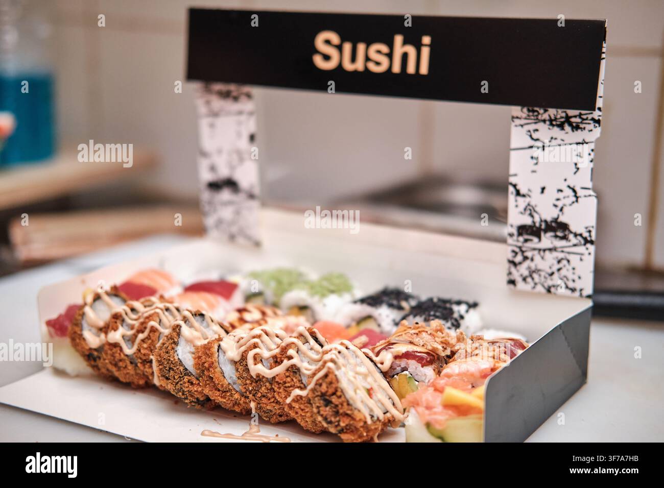 Sushi-Rollen präsentieren verschiedene Sorten in einer Mitnahmebox auf einer Theke Stockfoto