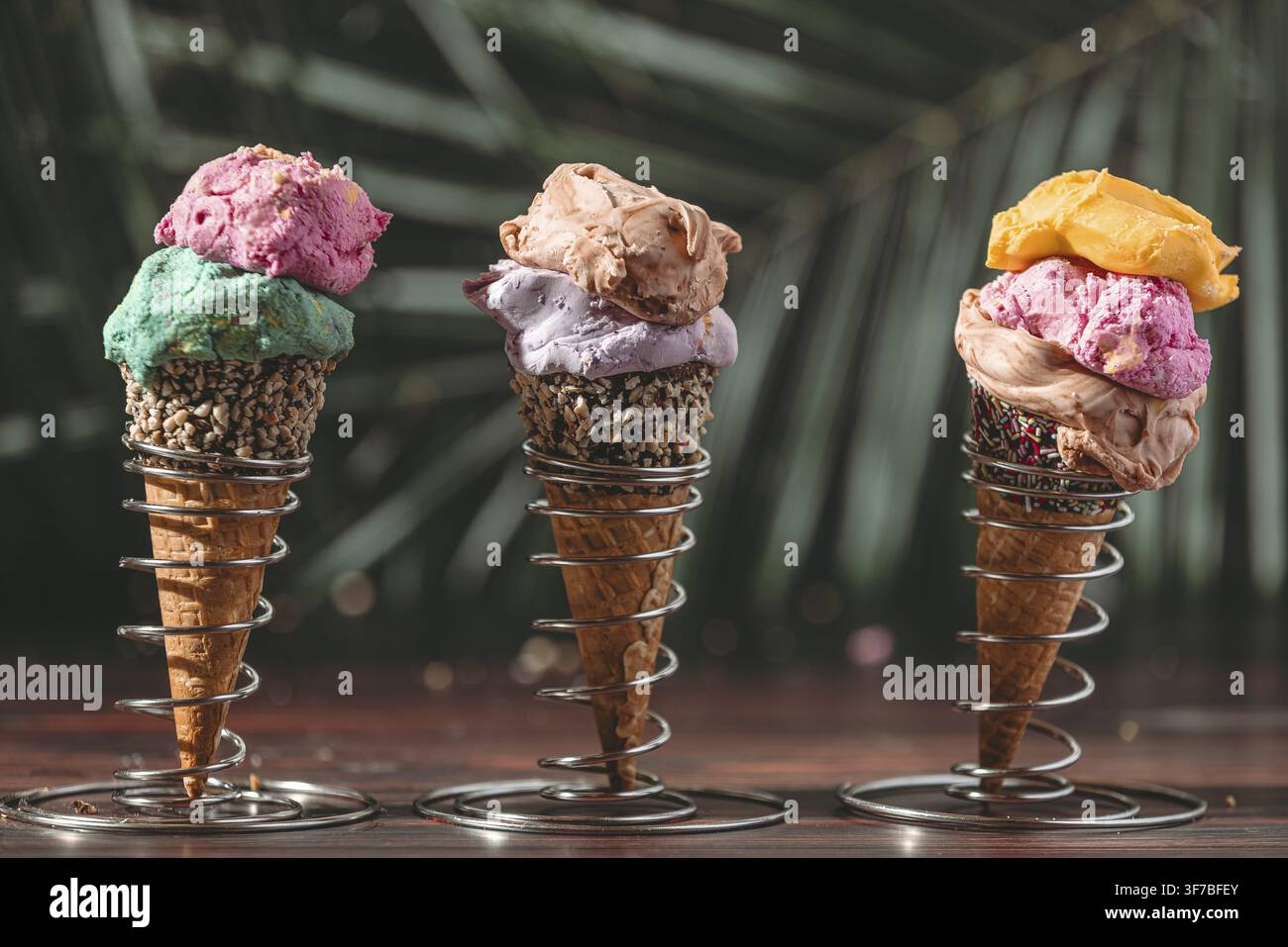 Drei Eiswaffeln mit farbenfrohem Eis vor einem tropischen Hintergrund Stockfoto