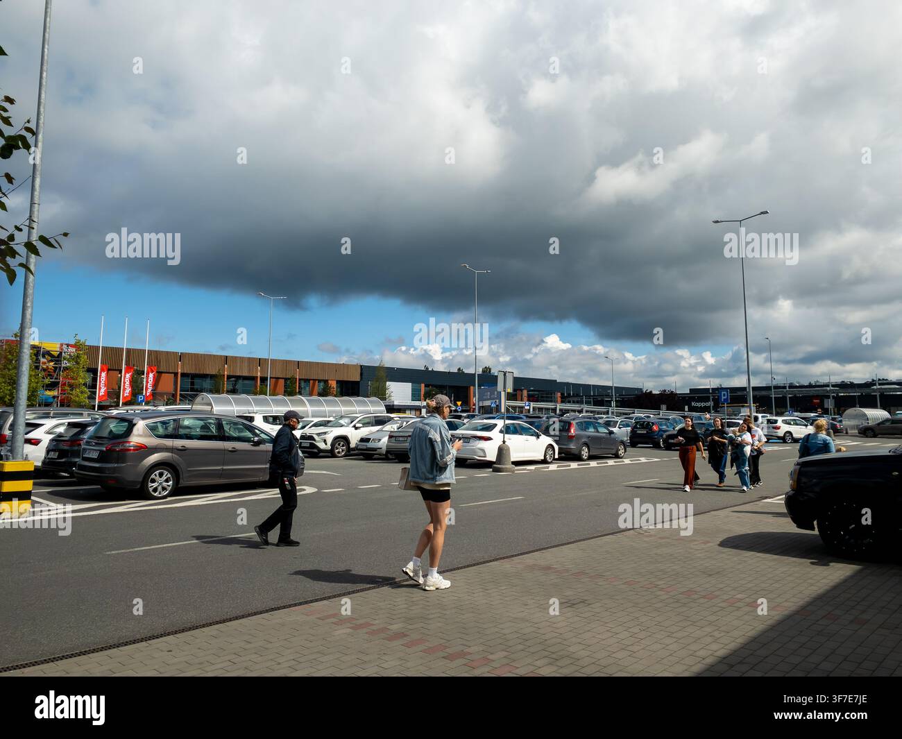 Danzig, Polen - 10. Juli 2026: Blick auf einen überfüllten Einzelhandelsparkplatz mit Fußgängern, die in der Nähe von Autos unter einem bewölkten Himmel gehen, was Einkaufsmuster und urbane Einzelhandelsaktivitäten darstellt Stockfoto