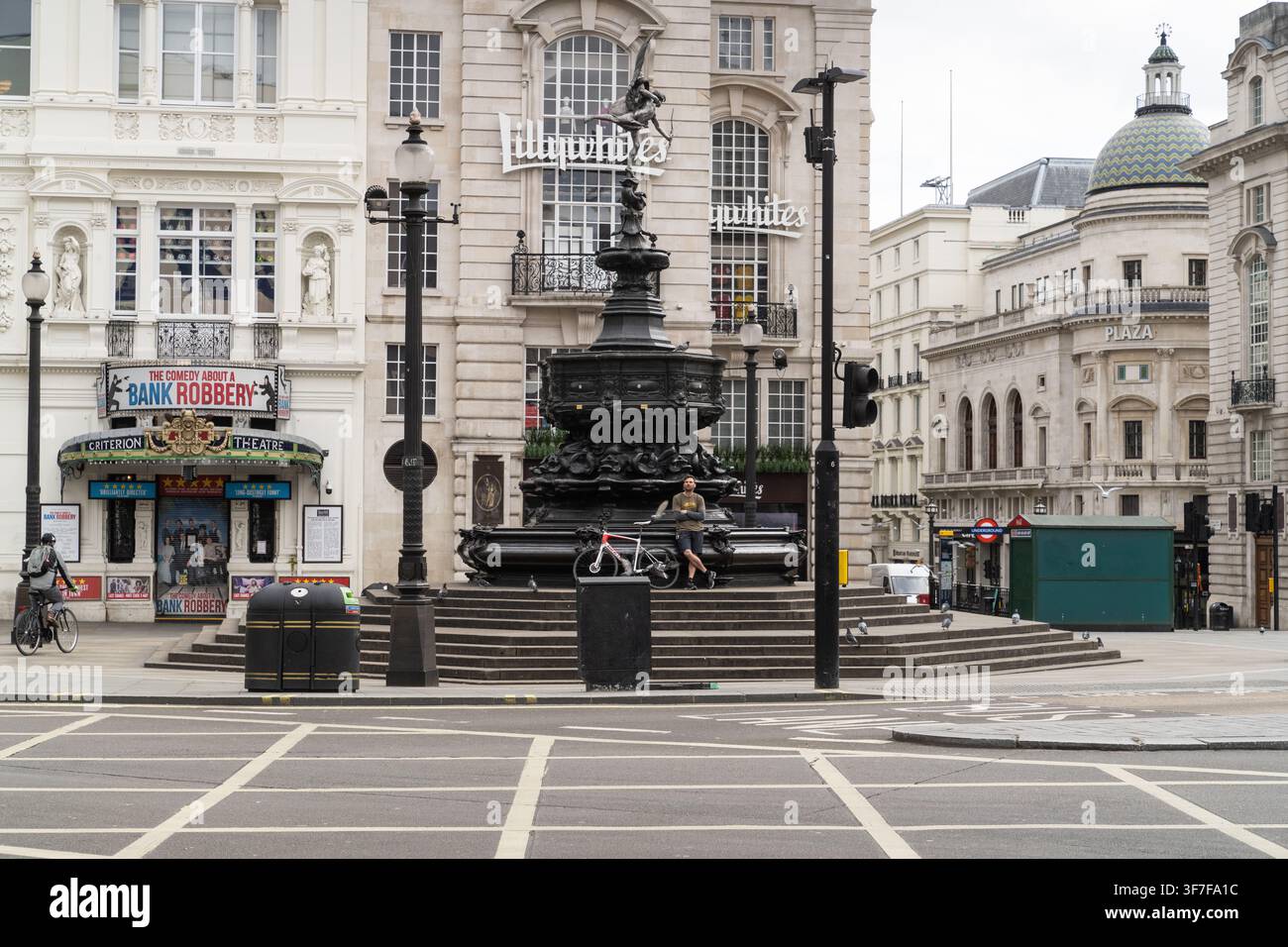Während der COVID-Lockdown-Phase im Vereinigten Königreich ruht ein einsamer Radfahrer an der Shaftesbury Memorial Fountain in einem verlassenen Piccadilly Circus, London. Stockfoto
