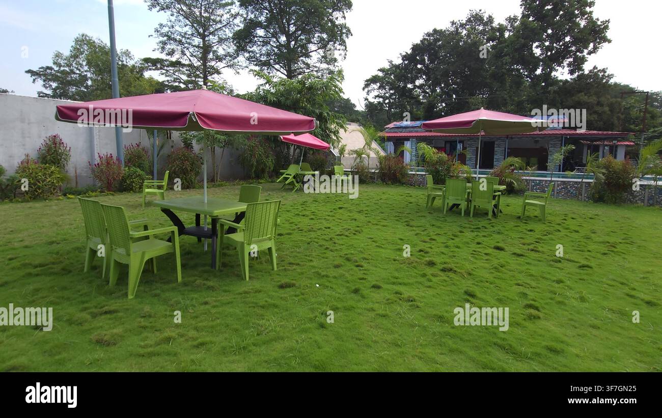 Gartenterrasse mit Tischen und rosa Sonnenschirmen auf einem grünen Rasen, Schirm Stockfoto