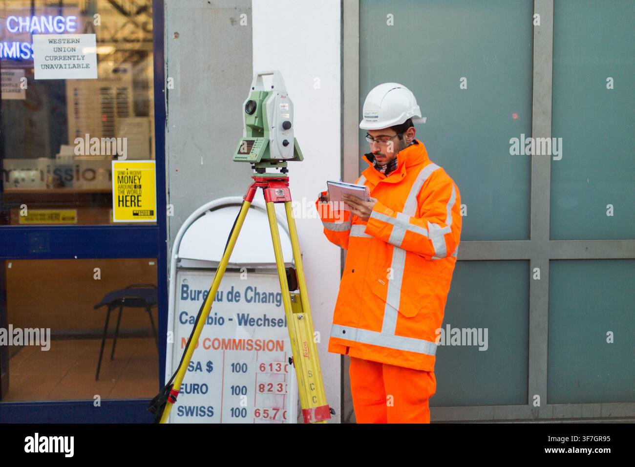 Ein Vermesser verwendet eine Totalstation für präzise Messungen in der Nähe des Victoria Station in Westminster, London, wahrscheinlich für städtische Infrastruktur. Stockfoto