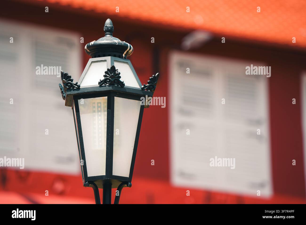 Eine vertikal ausgerichtete Mittel-Nahaufnahme eines klassischen schwarzen ornamentalen Straßenlaternen mit mattierten Glasscheiben. Die Laterne hebt sich von einem weichen Stockfoto
