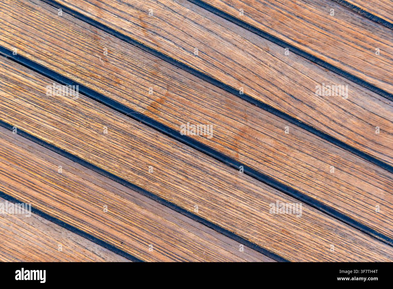 Nahaufnahme von Teakholzdecking auf einer Segelyacht, das eine saubere nautische Textur und einen nahtlosen Hintergrund erzeugt. Konzept von Marinedesign, Luxusbootfahren Stockfoto