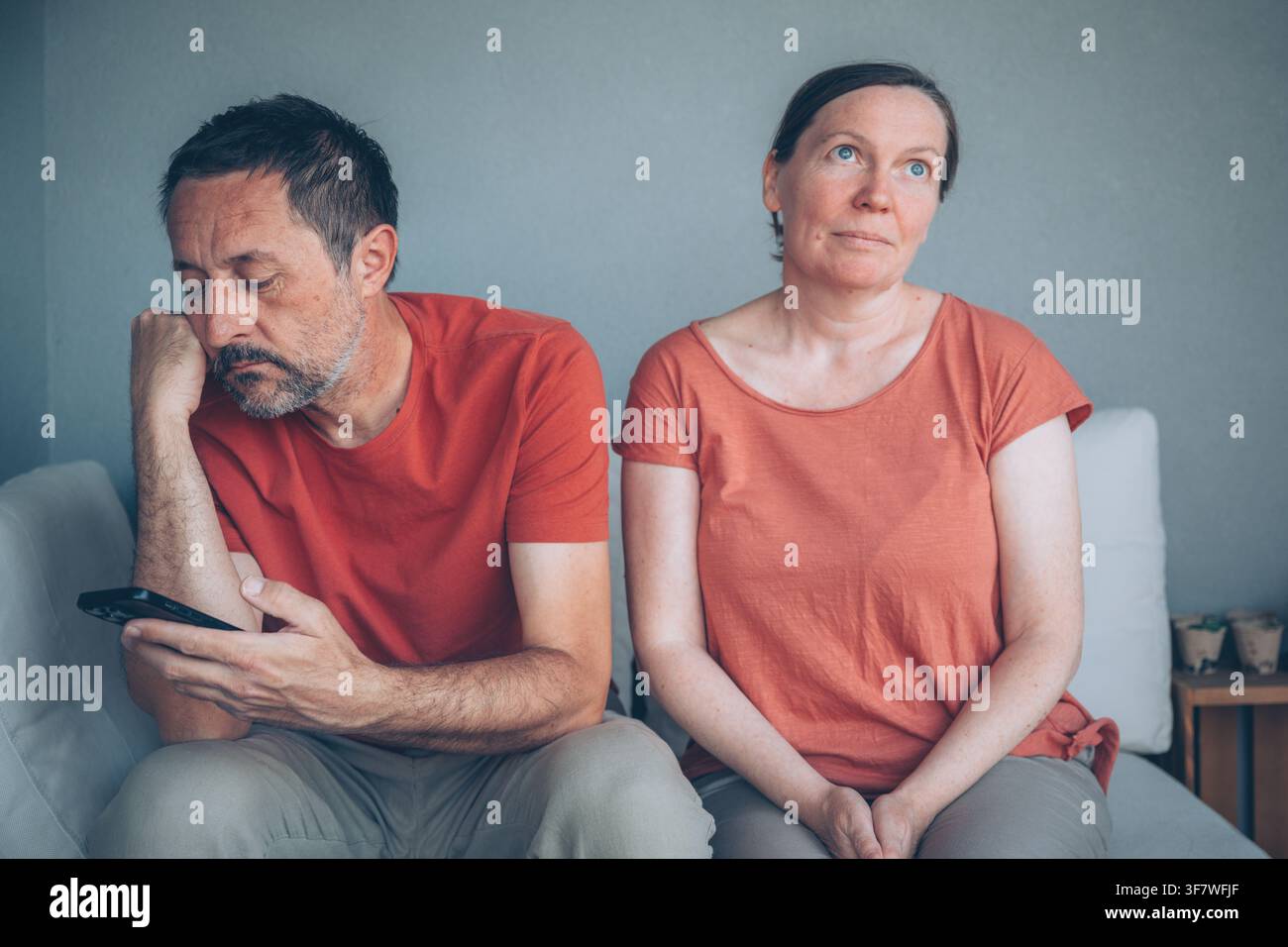 Mann und Frau überprüfen Handys während eines ernsten Gesprächs zu Hause, Technologie, Verdacht und moderne Beziehungsprobleme, selektiver Fokus Stockfoto