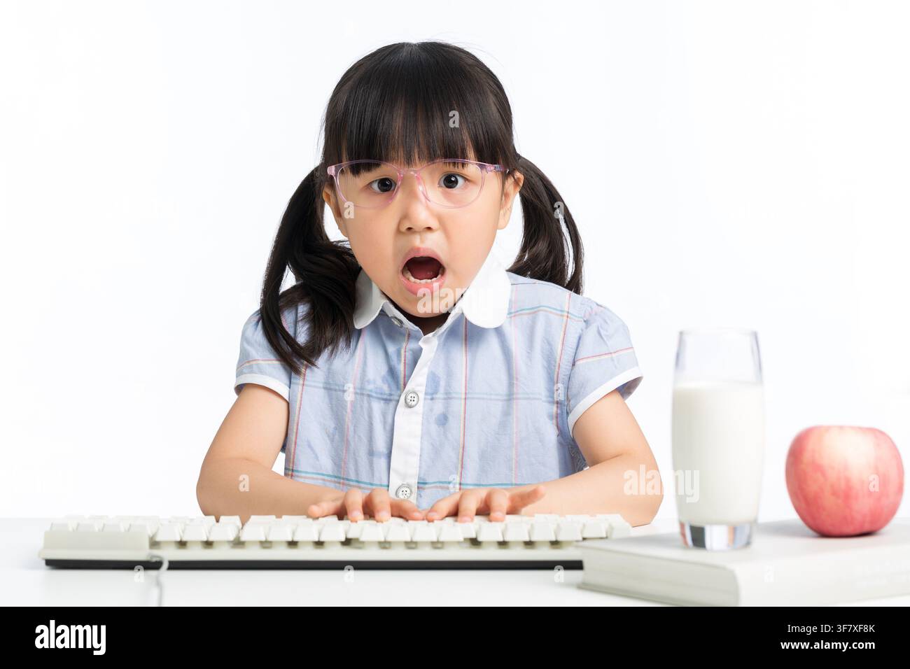 Überraschte Frau mit offenem Mund, die eine Computertastatur auf dem Schreibtisch benutzt Stockfoto