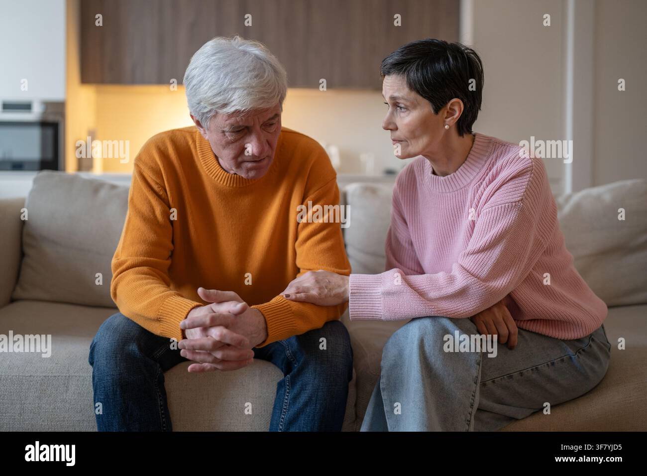 Besorgte, aufmerksame ältere Ehefrau unterstützt emotional gestressten Ehemann, der zu Hause auf dem Sofa sitzt. Stockfoto