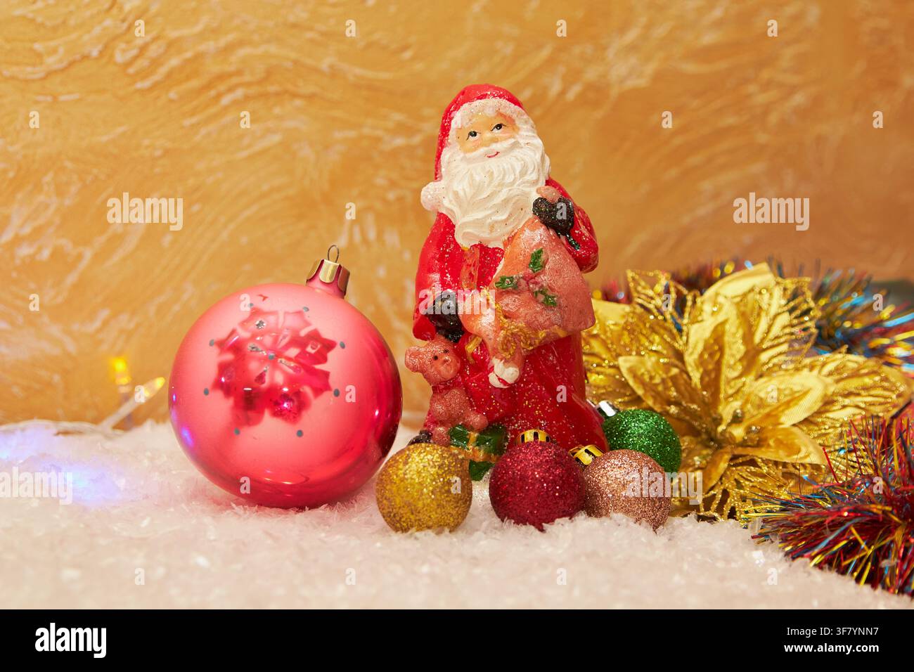 schöne Figur Claus im Schnee mit Kugeln, die mit leuchtenden Dekorationen verziert sind Stockfoto