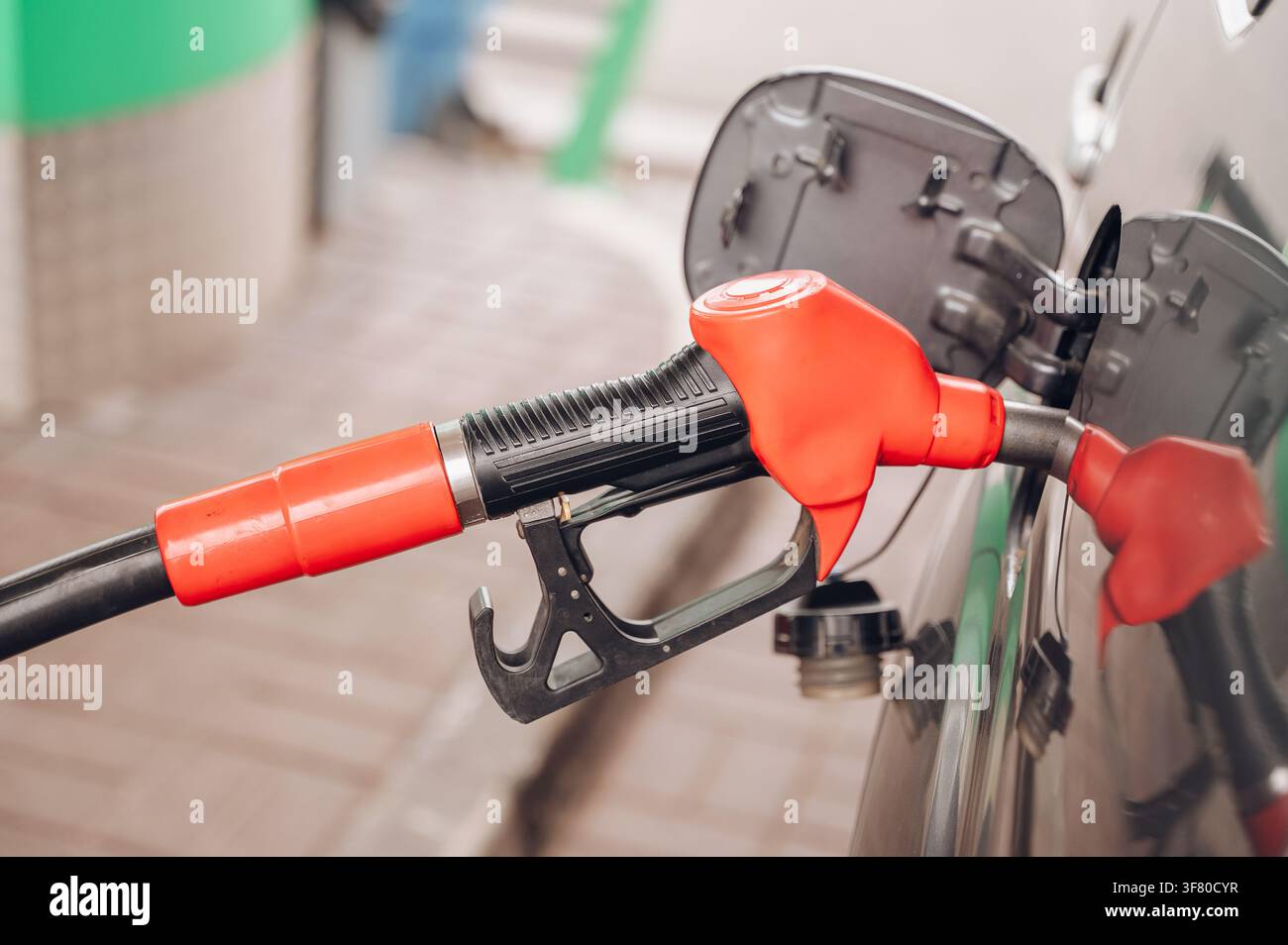Roter Kraftstoffschlauch, der in den Benzintank eines Autos an einer Tankstelle eingesetzt wird, Nahaufnahme, Kraftstoffbetankung und Verkehrswirtschaftskonzept. Hochwertiges Foto Stockfoto