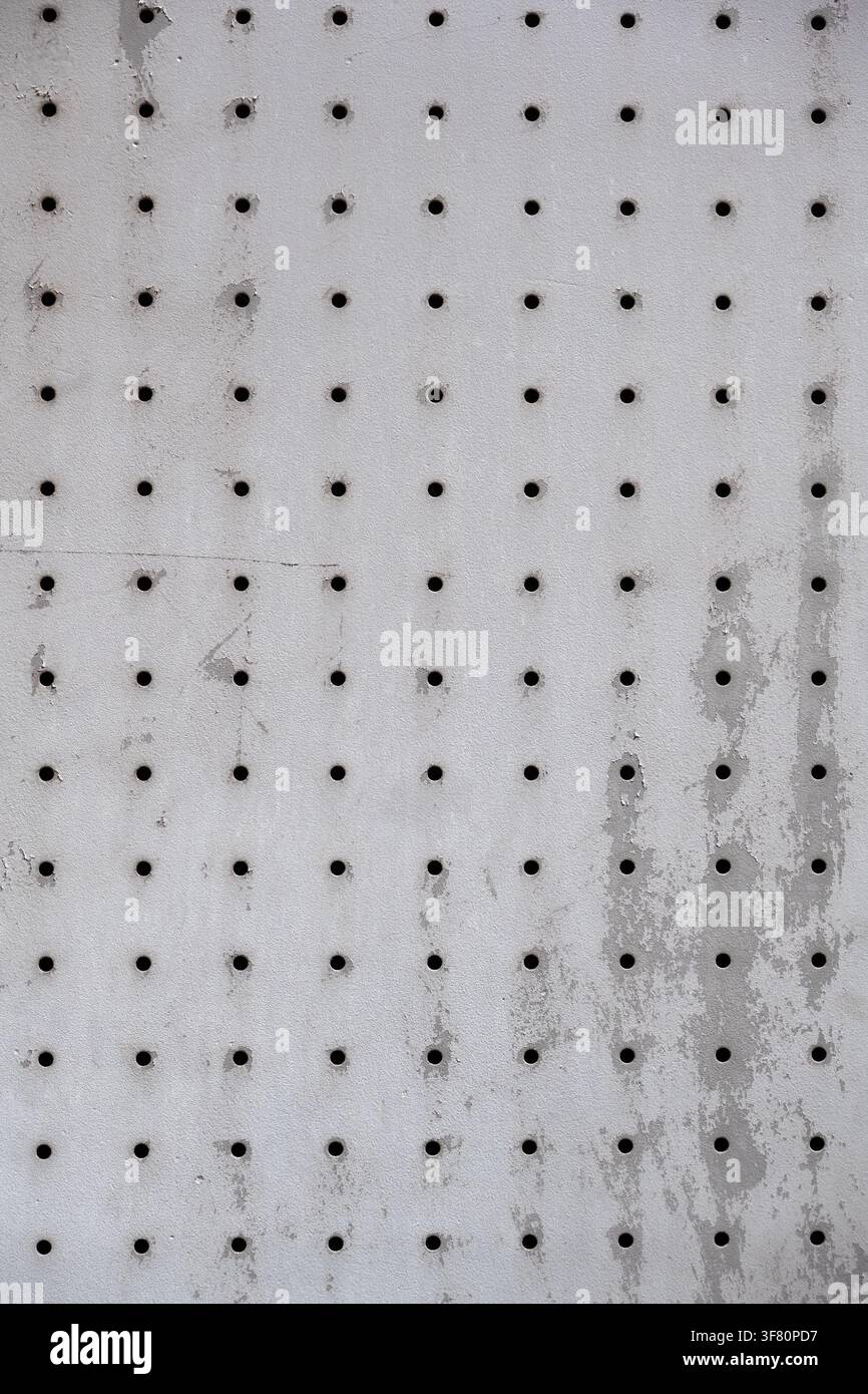 Abstrakt aus perforiertem Metallblech, das mit vielen Löchern in regelmäßigem Muster durchbohrt ist Stockfoto