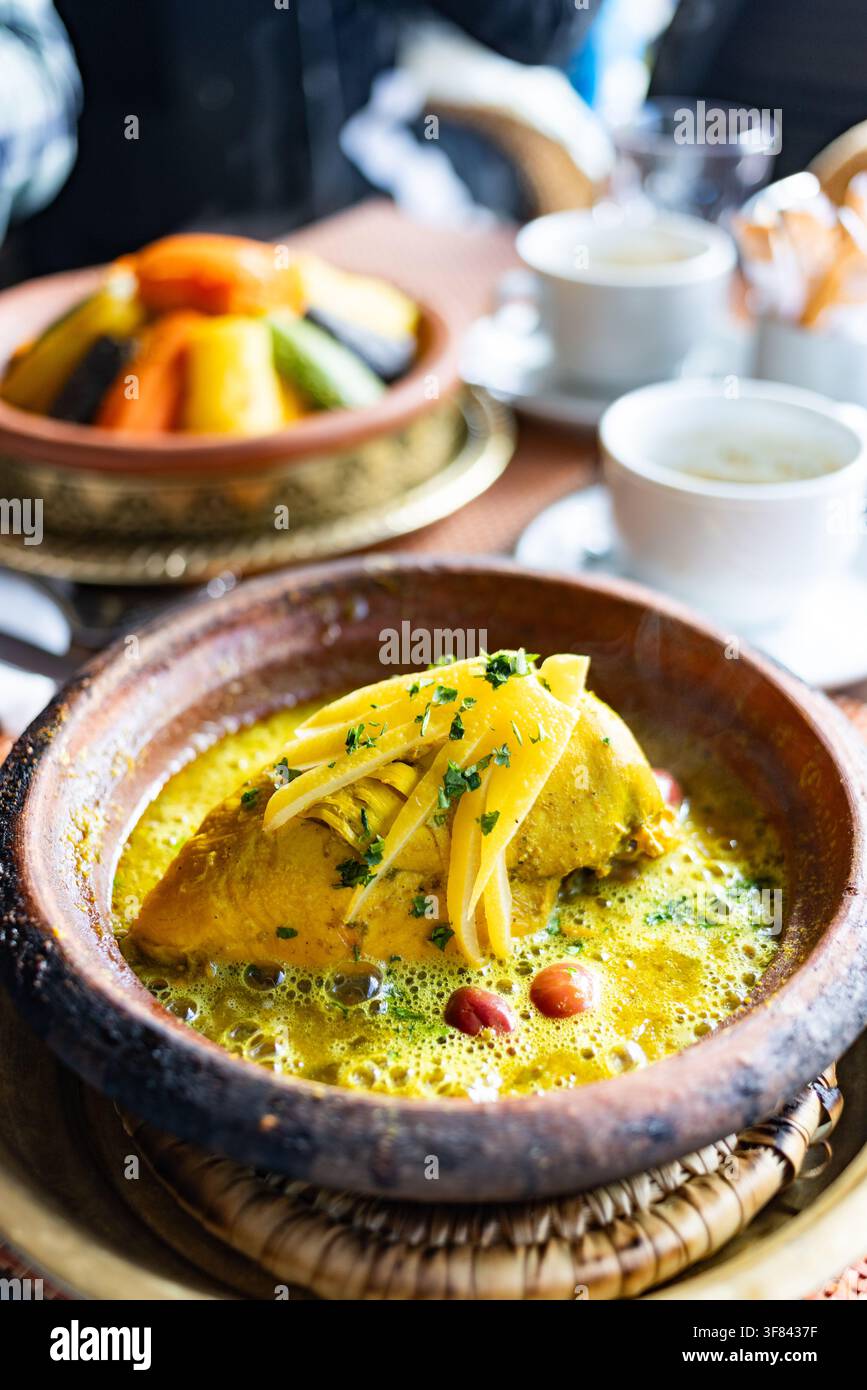 Erleben Sie traditionelle marokkanische Tajine, serviert mit Couscous auf einem Esstisch in einer lokalen Umgebung Stockfoto
