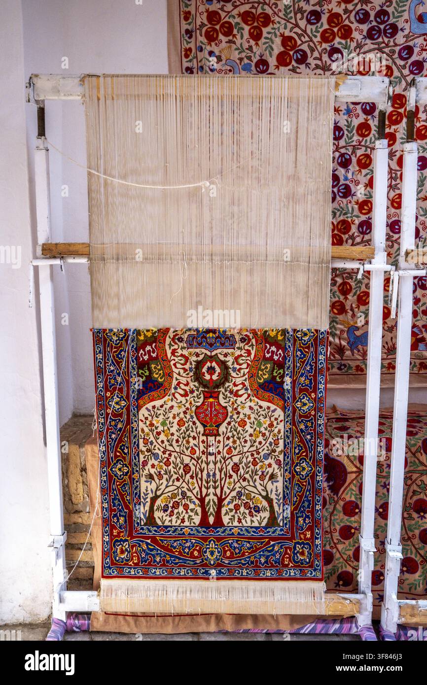 Handwerker weben traditionellen Teppich am Webstuhl im historischen Itchan Kala in Chiwa, Usbekistan, und präsentieren kunstvolle Muster und Handwerkskunst Stockfoto