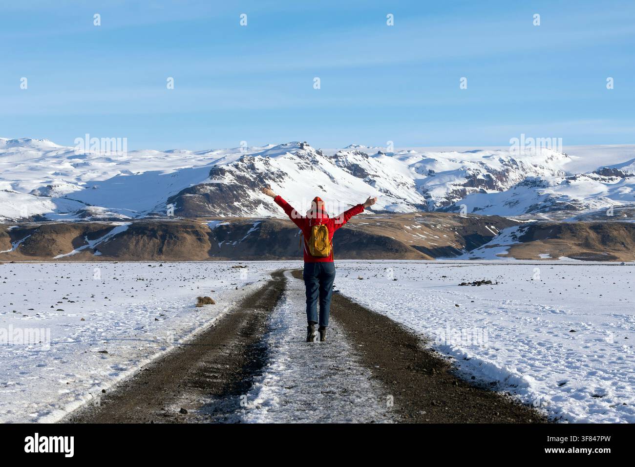 Asiatische Frau in roter Jacke läuft auf einem Feldweg in Landmannalaugar in den Hochlanden Islands Stockfoto