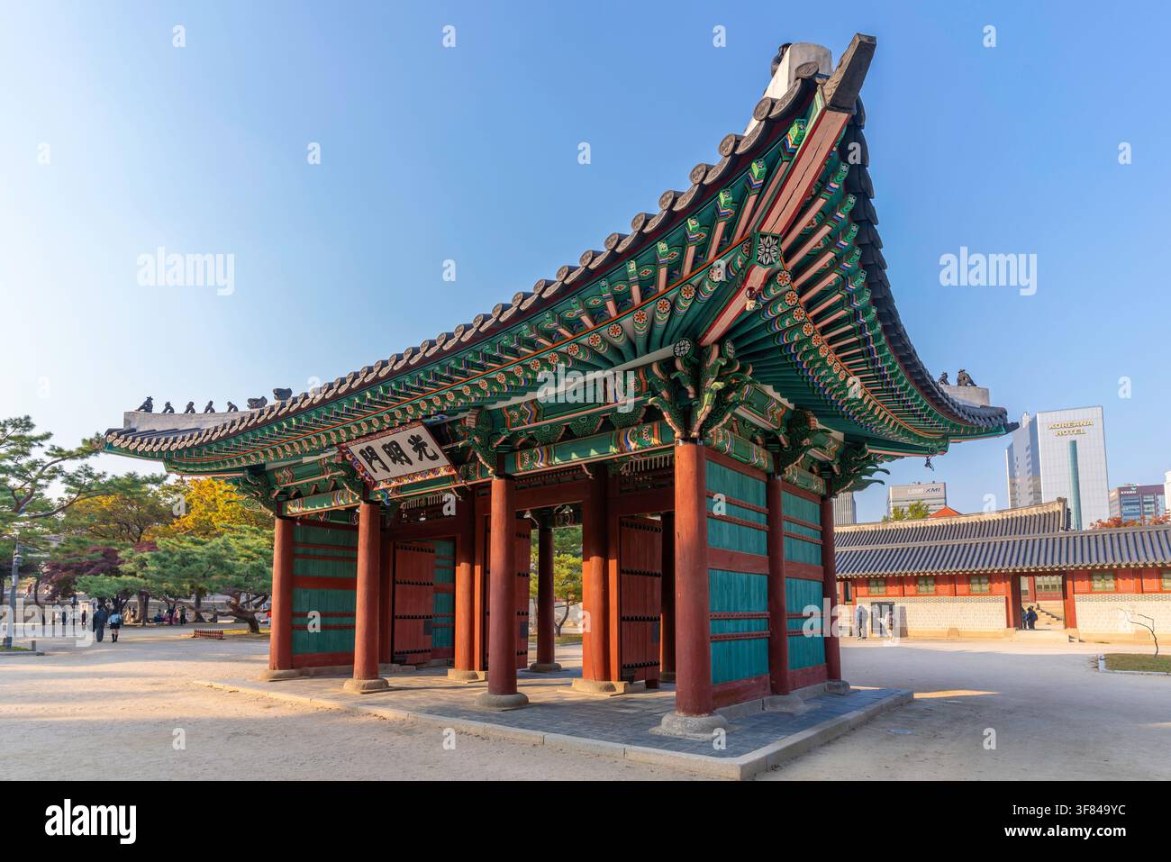 Ansicht des Gwangmyeongmun-Tores auf dem Gelände des Deoksugung-Palastes mit modernen Gebäuden im Hintergrund Stockfoto