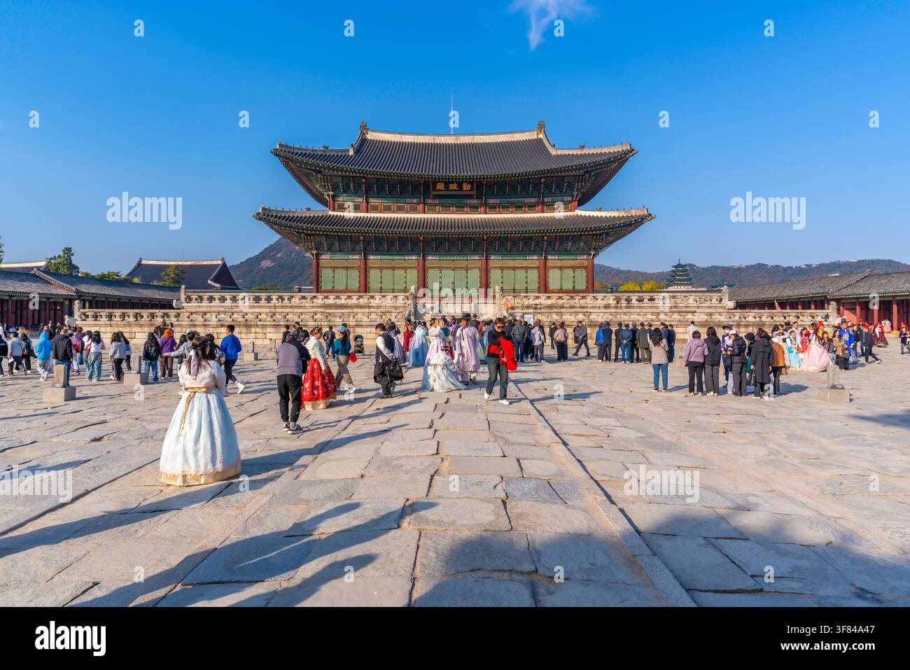 Damen tragen koreanische Hanbok im Gyeongbokgung-Palast an einem sonnigen Tag in Seoul, während Touristen die historische Stätte besuchen und erkunden Stockfoto