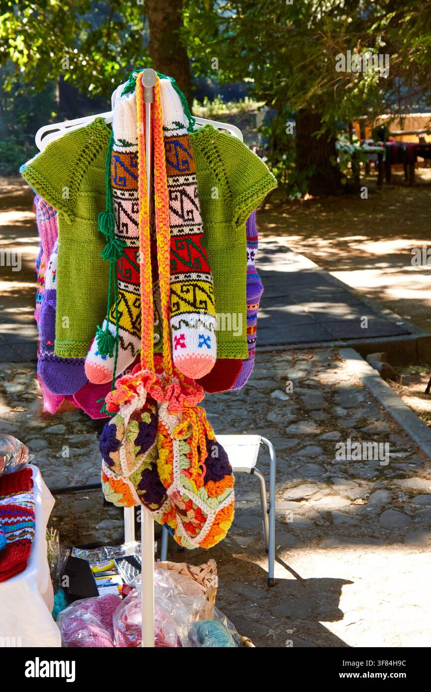 Traditionelle bulgarische Strickkleidung wird auf einem Ständer auf einem Festival ausgestellt, mit hellen Farben und einzigartigen Mustern in einer Außenumgebung Stockfoto