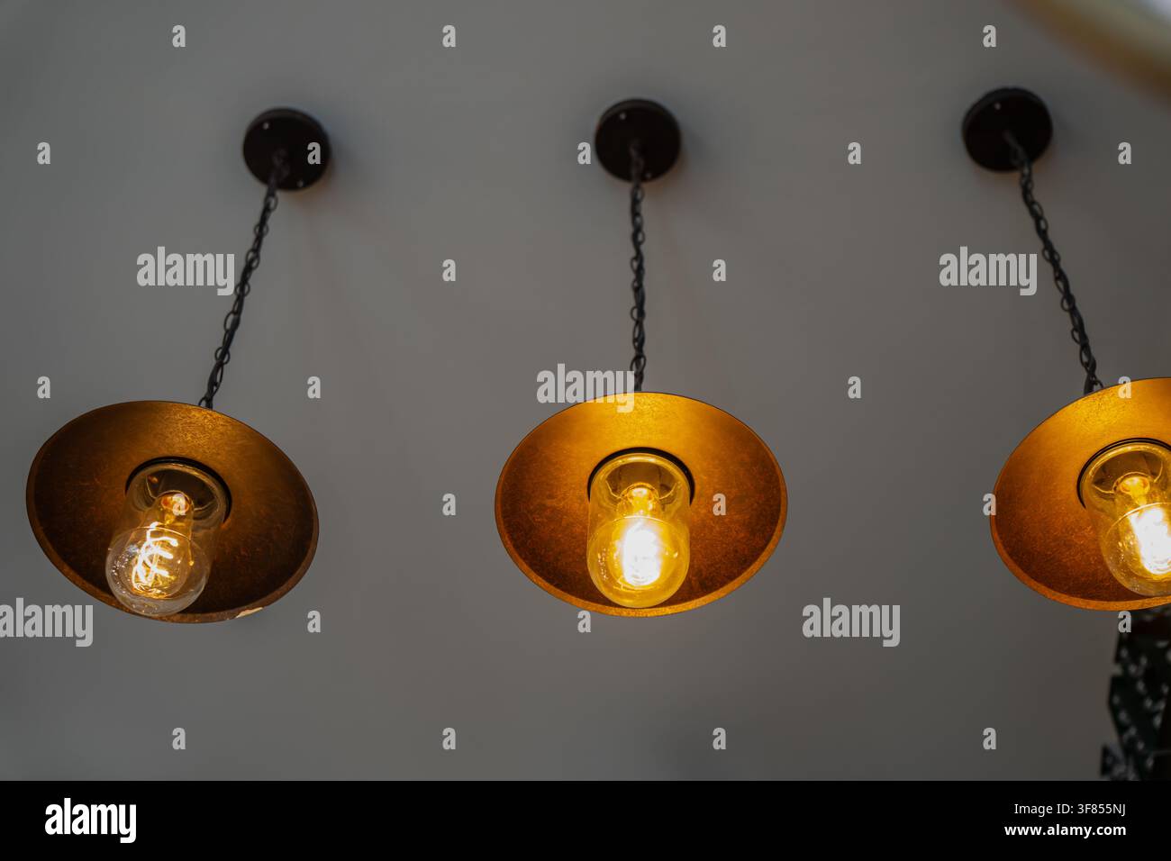 Rustikale metallische Pendelleuchten mit beleuchteten Glaskolben, im antiken Industriedesign des Interieurs, warmer Beleuchtung und gemütlicher Atmosphäre Stockfoto