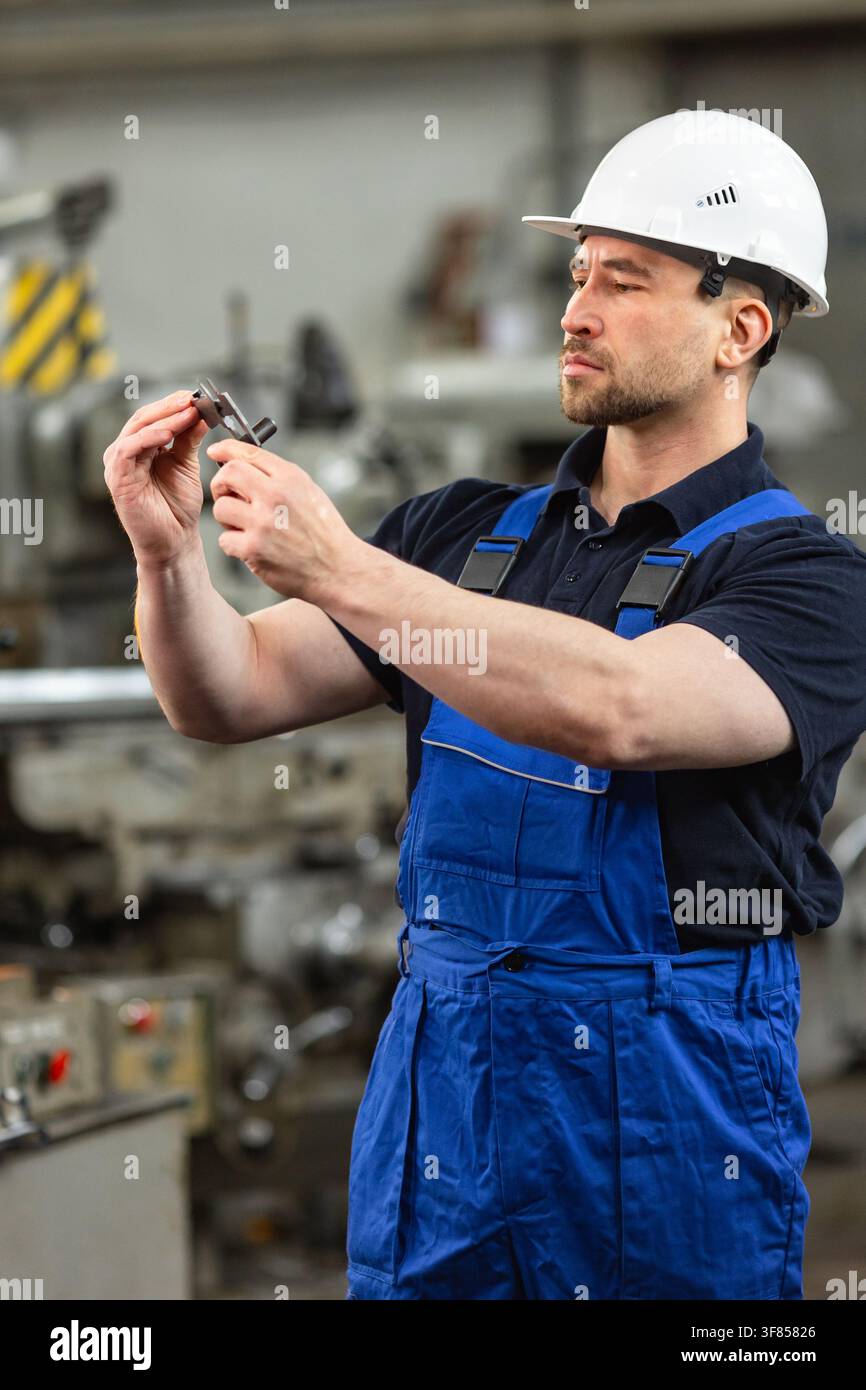 Industriearbeiter inspiziert Metallteil mit Bremssattel in der Fabrik Stockfoto