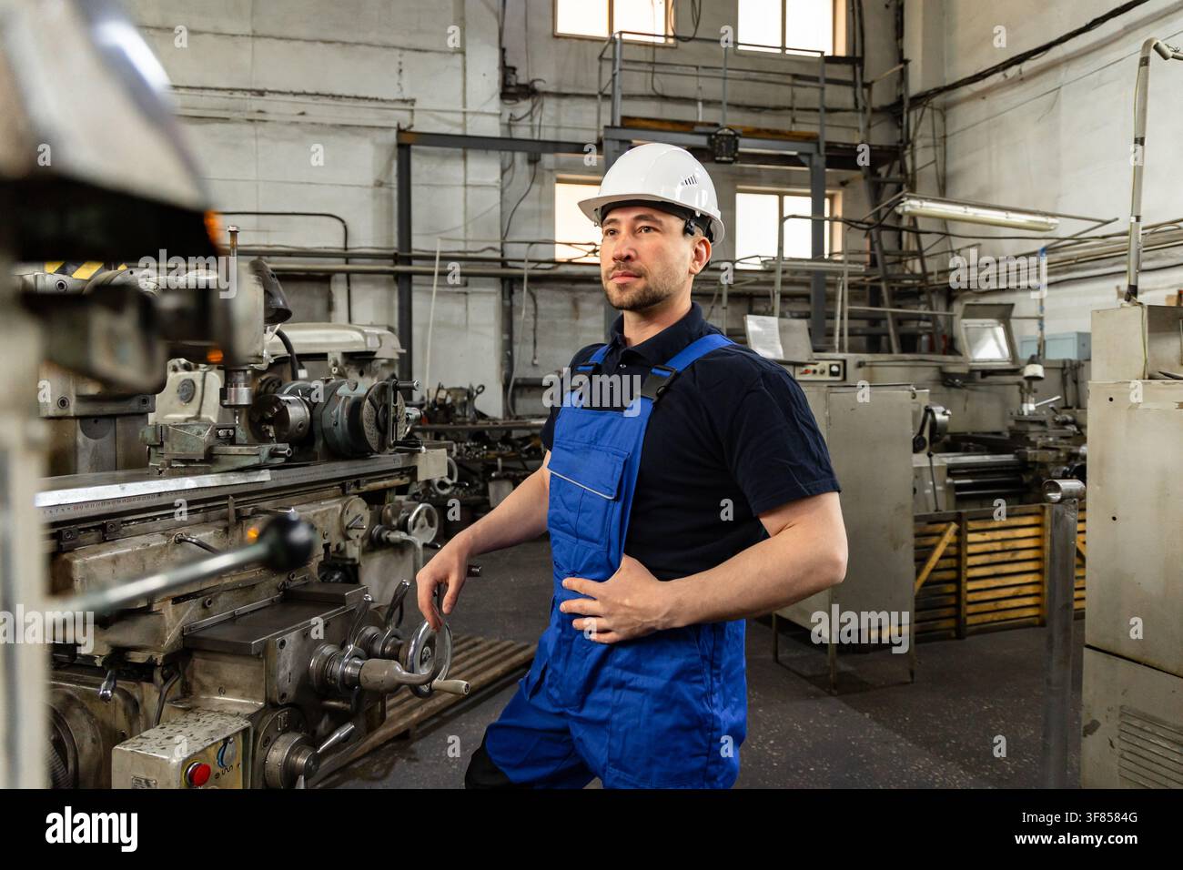 Professioneller Maschinist steht neben einer Industriemaschine in der Fabrik Stockfoto