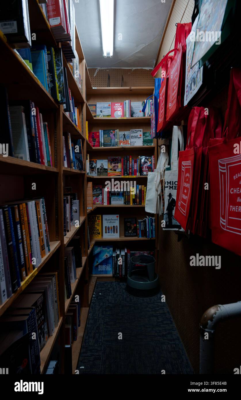 Schmaler Gang voller Bücher und Tragetaschen in einem gemütlichen Buchladen in Columbus Stockfoto