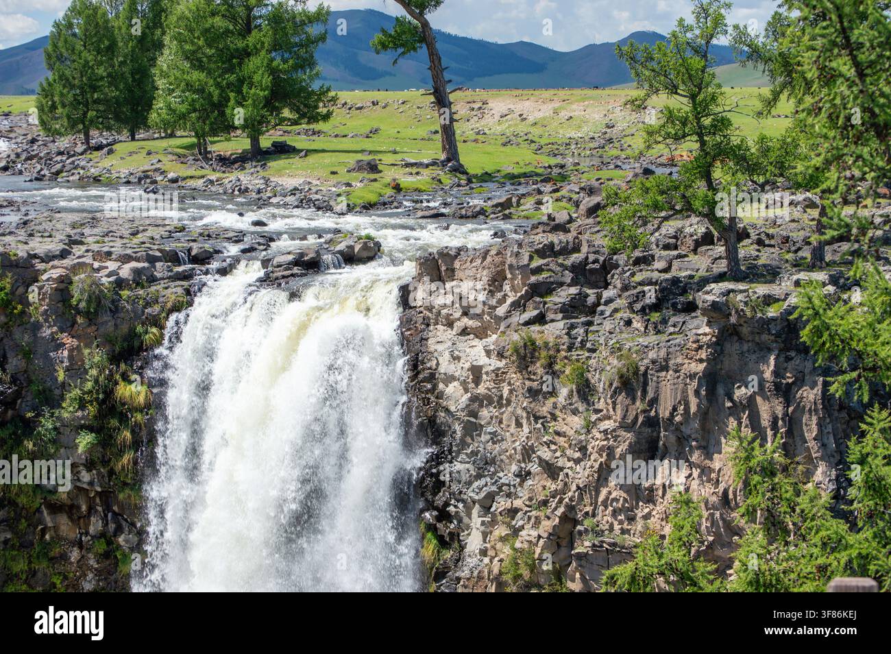 Orchon-Tal, Mongolei – 4. August 2026: Touristen am Fluss über dem Orchon-Wasserfall (Ulaan Tsutgalan), mit grasenden Pferden auf der Steppe. Stockfoto