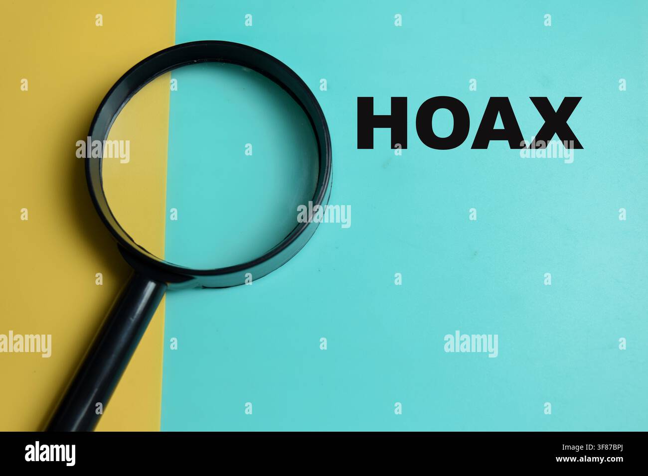 Konzept eines Hoaxes, geschrieben auf farbigem Hintergrund mit Lupe. Stockfoto