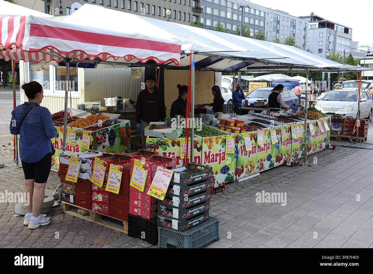 Ein lebhafter lokaler Marktstand in Lahti, Finnland, gefüllt mit frischem Gemüse, Beeren und regionalen Produkten unter einem blau-weißen Zelt. Stockfoto