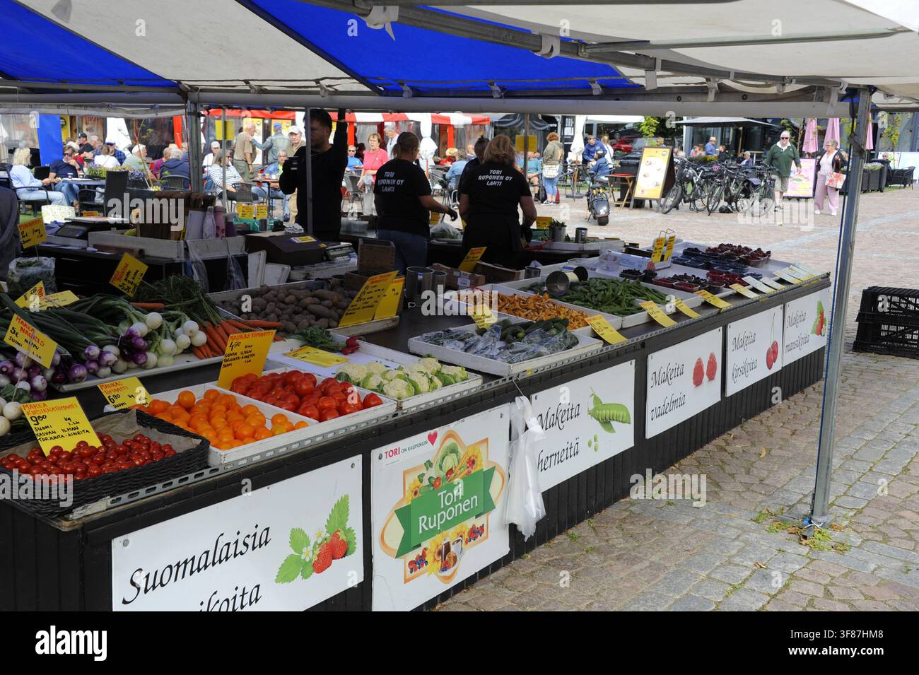 Ein lebhafter lokaler Marktstand in Lahti, Finnland, gefüllt mit frischem Gemüse, Beeren und regionalen Produkten unter einem blau-weißen Zelt. Stockfoto