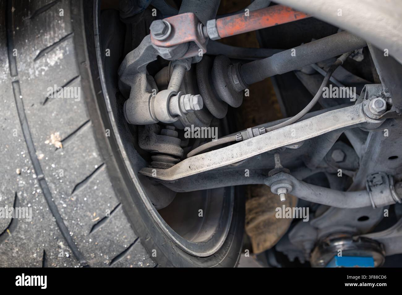 Detaillierte Ansicht von unten, die den hinteren Radstand, den CV-Gelenksatz, die oberen und unteren Querlenker, das Stabilisatorstutzenglied und den inneren Radkranz an einem Auto zeigt Stockfoto