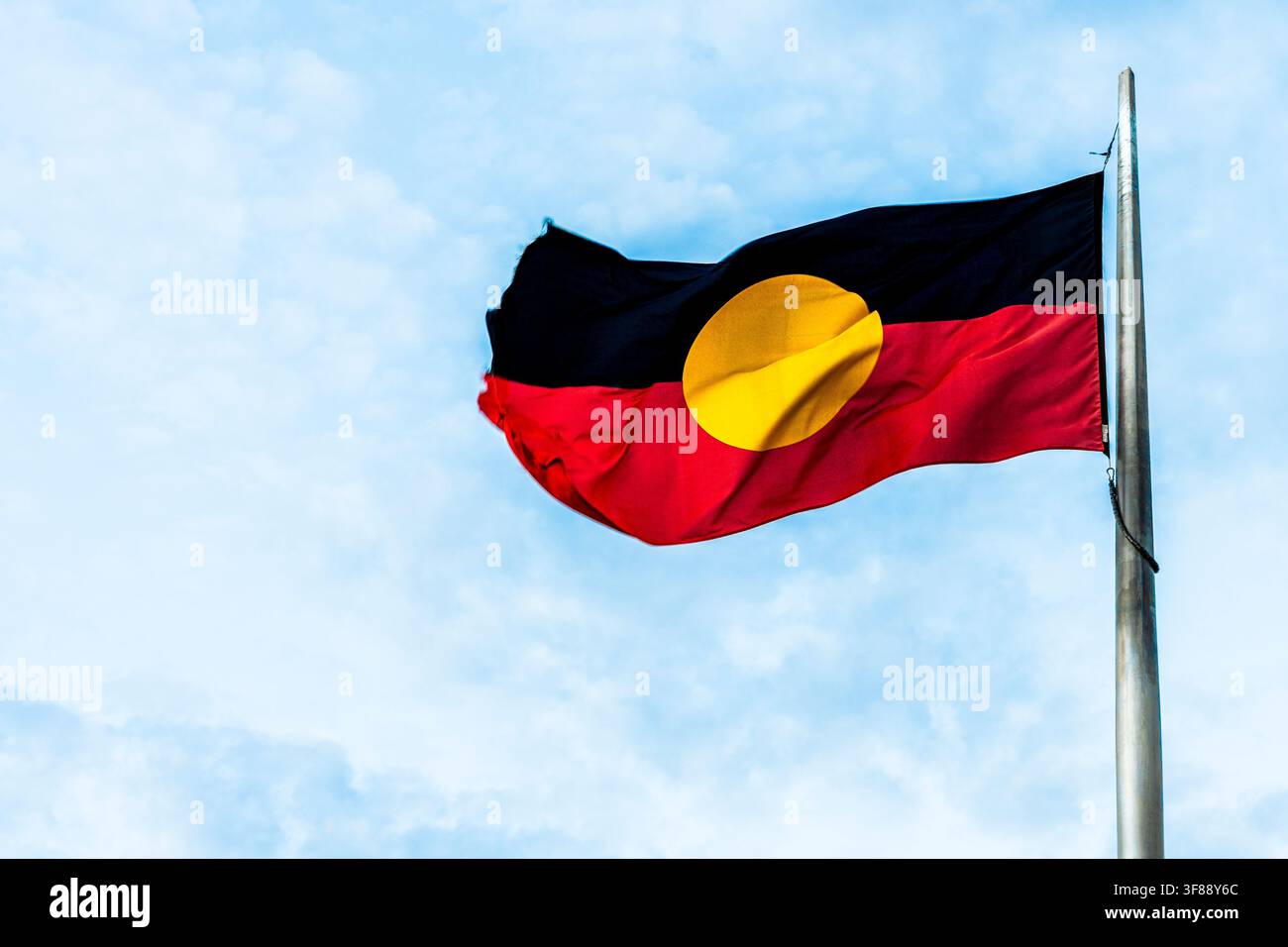 Rote, schwarze und gelbe Flagge der Ureinwohner Australiens, die im Wind in Alice Springs, Northern Territory, Australien weht Stockfoto