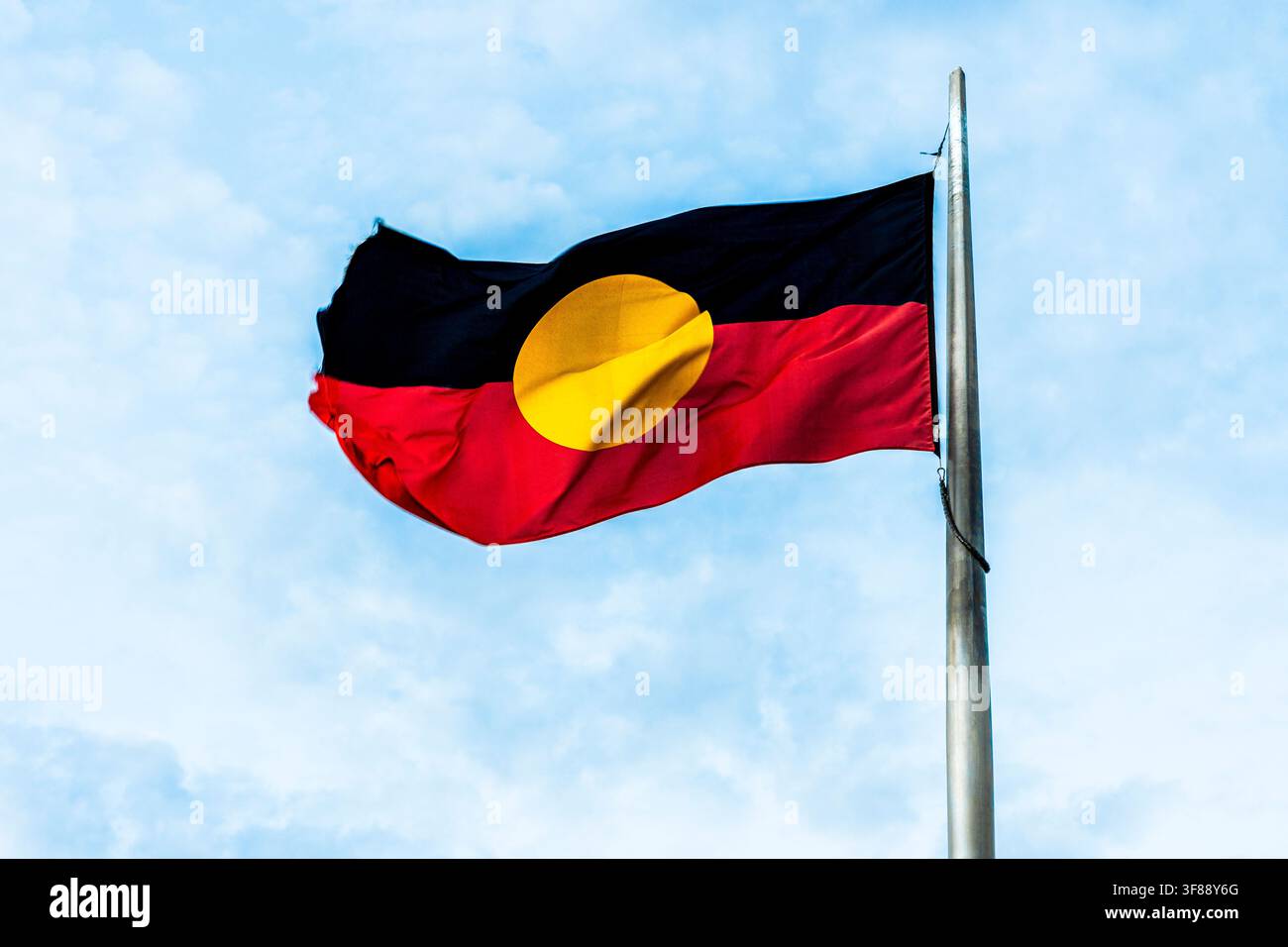 Rote, schwarze und gelbe Flagge der Ureinwohner Australiens, die im Wind in Alice Springs, Northern Territory, Australien weht Stockfoto