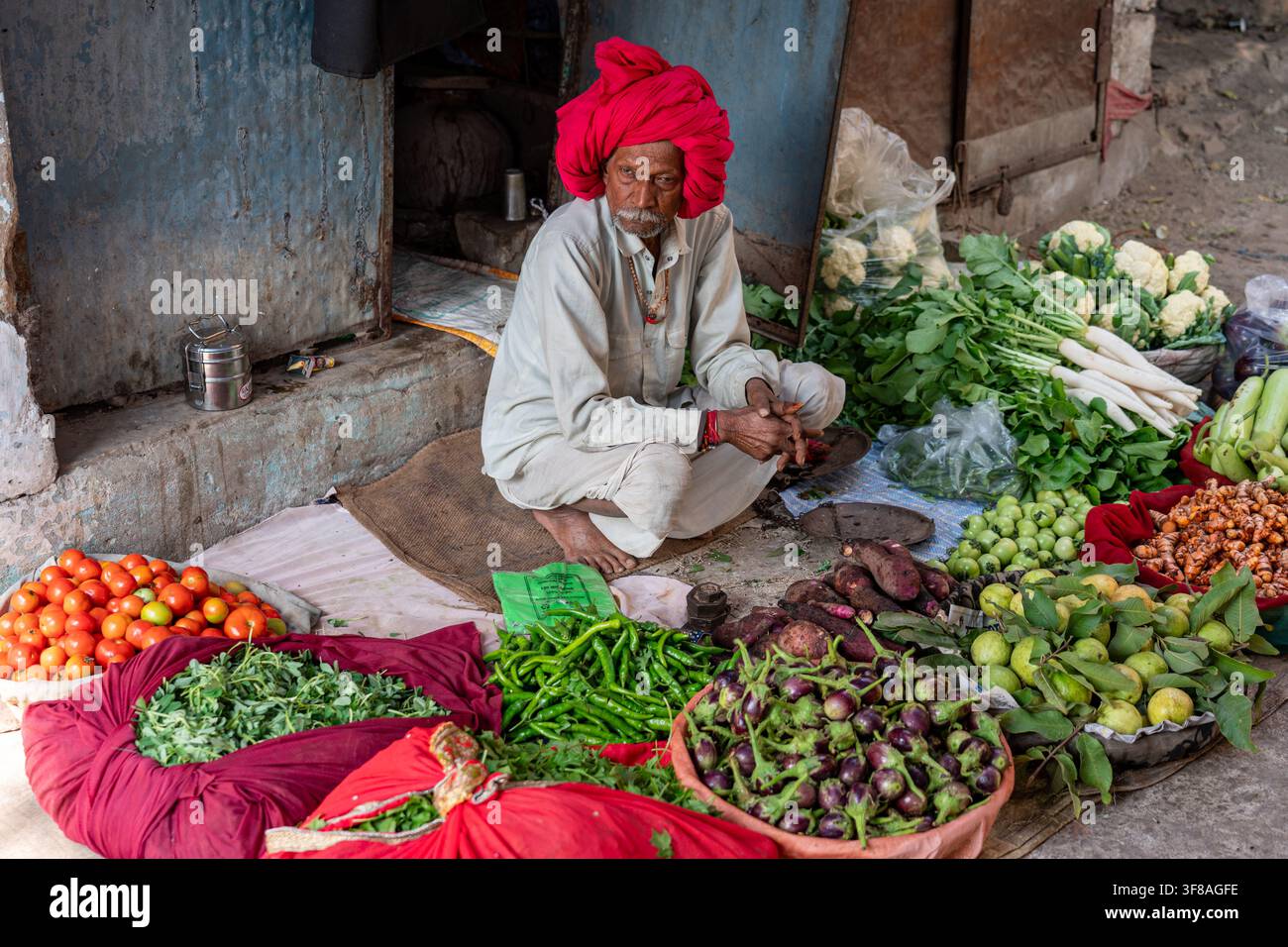 Indien. Rajasthan. Bundi. Ein alter Hindu, der einen roten Turban trägt, Gemüsehändler, sitzt vor seinem Stand // India. Rajasthan. Bundi. An Stockfoto