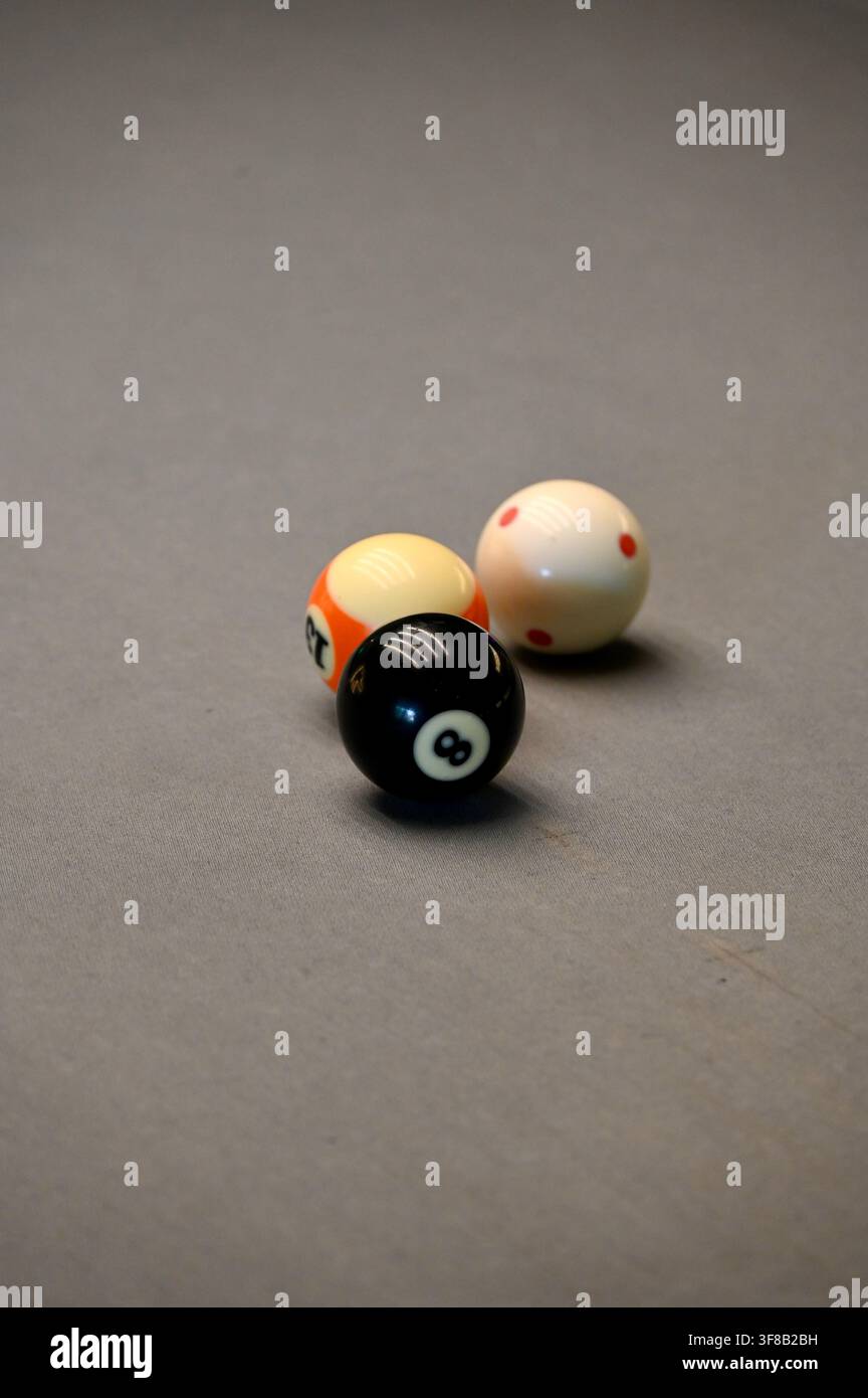 Kommerzielle Nahaufnahme eines schwarzen 8-Balls, der eng vor einem weiteren gestreiften Billardball auf einem grauen Billardtischfilz positioniert ist, wobei die Textur und die Spieldetails eingefangen werden. Stockfoto
