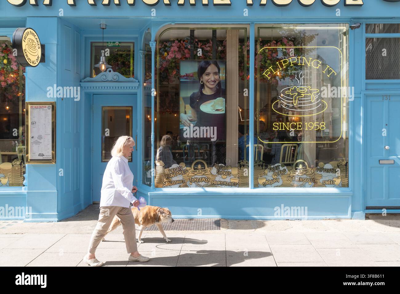 Eine Frau führt ihren Hund an My Old Dutch auf dem High Holborn vorbei und fängt das tägliche Leben außerhalb des historischen Londoner Pfannkuchen-Denkmals ein. Stockfoto