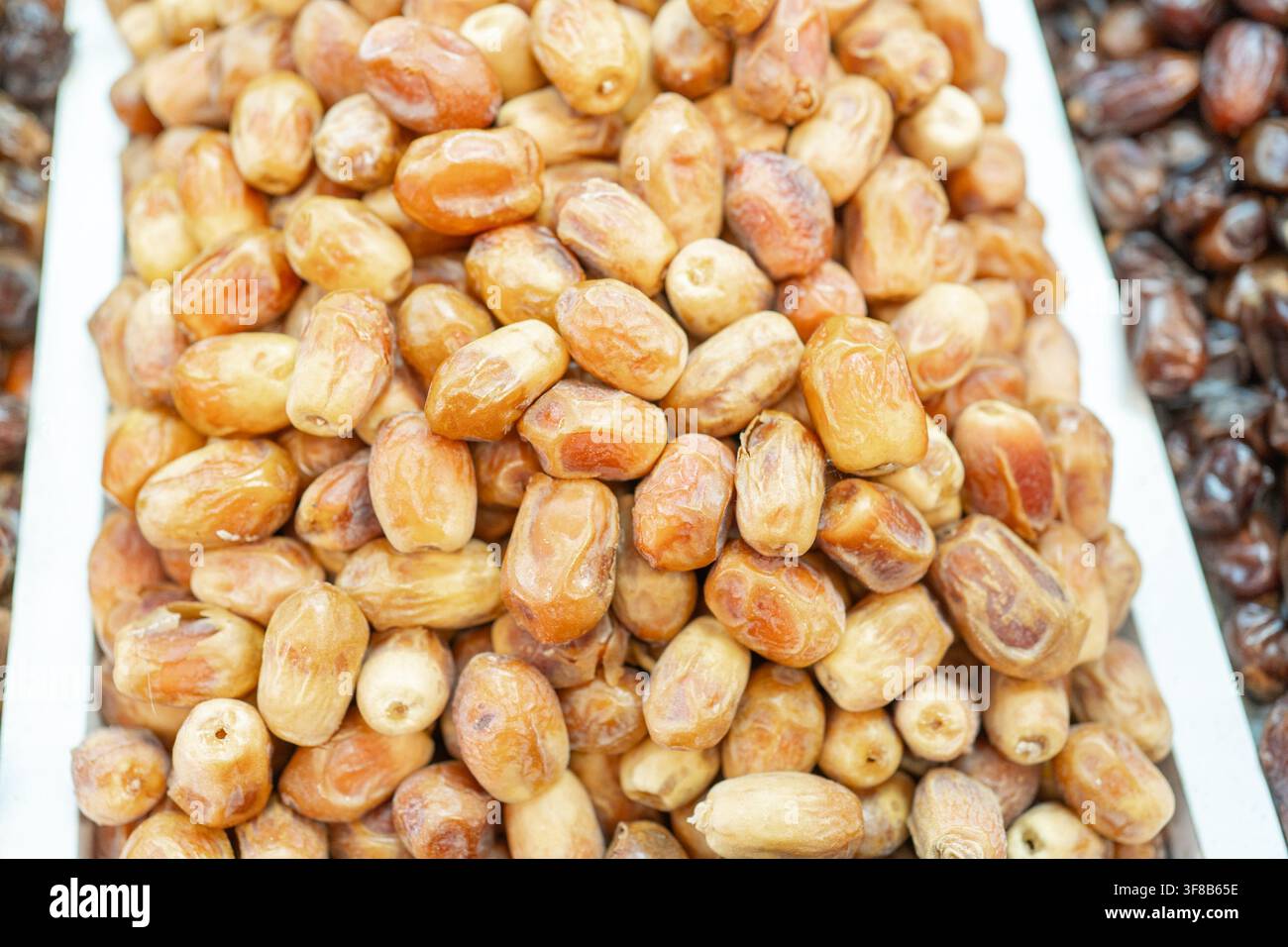 Top-Down-Nahaufnahme-Textur von getrockneten süßen Datteln, die an einem östlichen Lebensmittelmarktstand präsentiert werden. Ideales Hintergrund-Bild für gesunde Snacks, vegane Ernährung Stockfoto