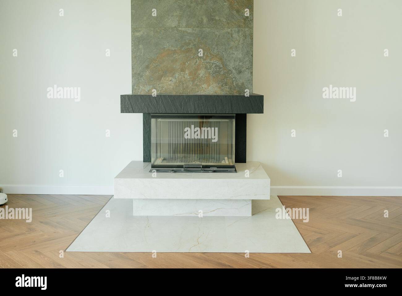 Eleganter moderner Kamin mit Natursteinverkleidung, der bis zur Decke reicht, in einem minimalistischen Wohnzimmer. Großer visueller Vorteil für Hausheizsysteme Stockfoto