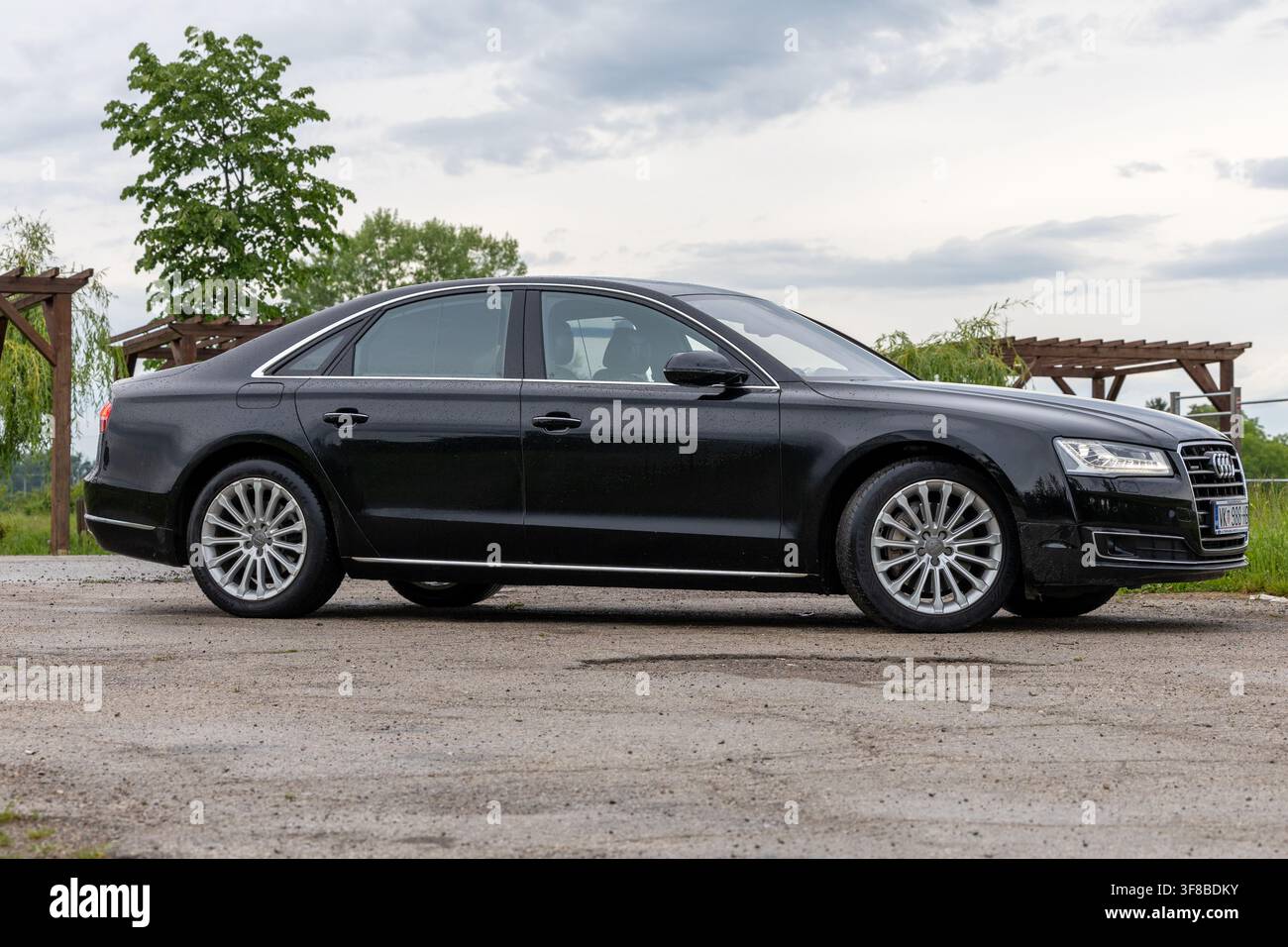 Vinkovci, Kroatien - 15. Mai 2026: Eine schwarze Audi-Luxussedan, die auf einem Schotterplatz unter einem bewölkten Himmel geparkt ist, betont Aluminiumräder und ein schlankes Seitenprofil Stockfoto