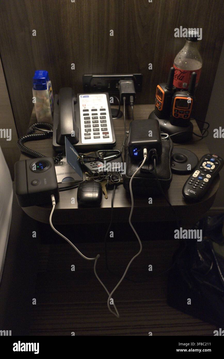 Tempe Arizona 4. August 2026, Unordentlicher Nachttisch im Hotel mit Handy, Ladegerät, Tums, Coke Zero, Fernbedienung und Brieftasche. Stockfoto