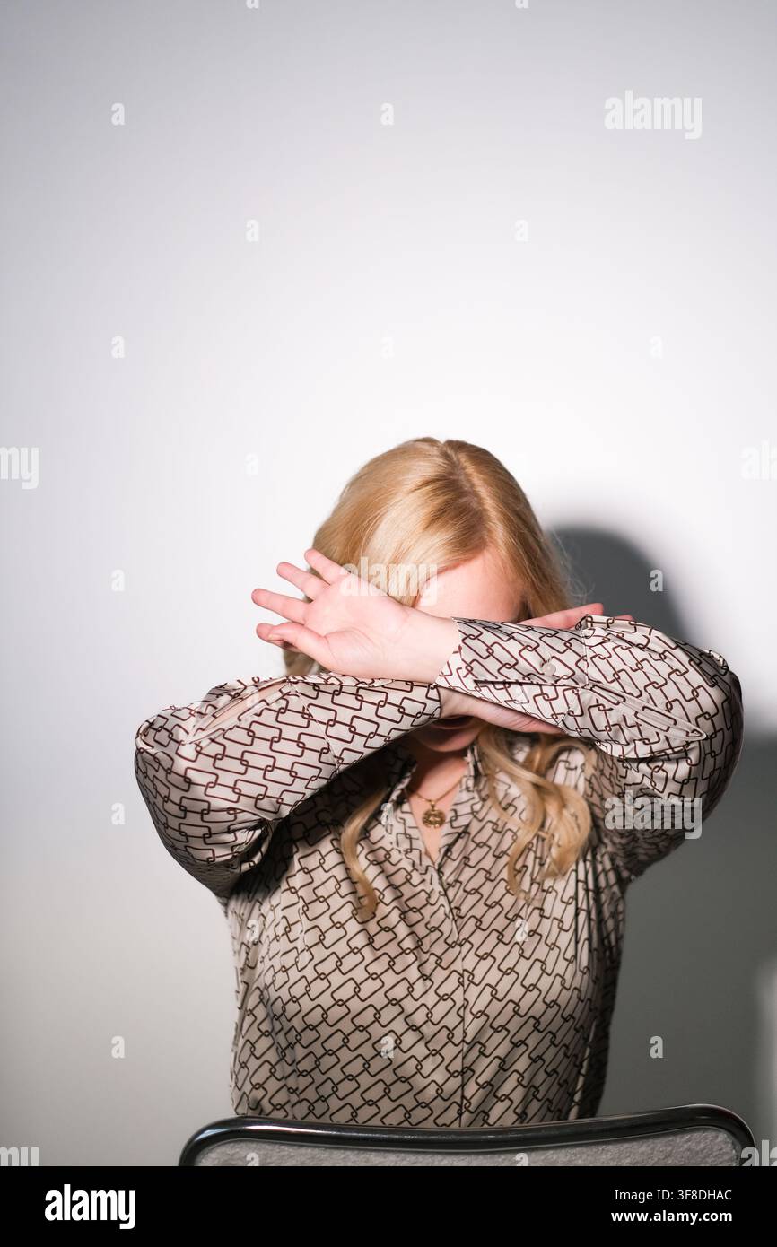 Russland, Moskau, 02.02.2024 Frau, die ihr Gesicht mit ihren Armen und Händen verdeckt, Konzept von Schutz, Scham oder Privatsphäre. Soziale Probleme und emotionaler Ausdruck Stockfoto