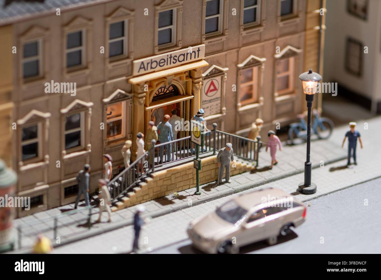 WIEN, ÖSTERREICH, 26. November 2022: Ein detailliertes Miniatur-Straßendiorama zeigt kleine Figuren, die ein Gebäude namens Arbeitsamt neben einem Gehweg betreten, l Stockfoto