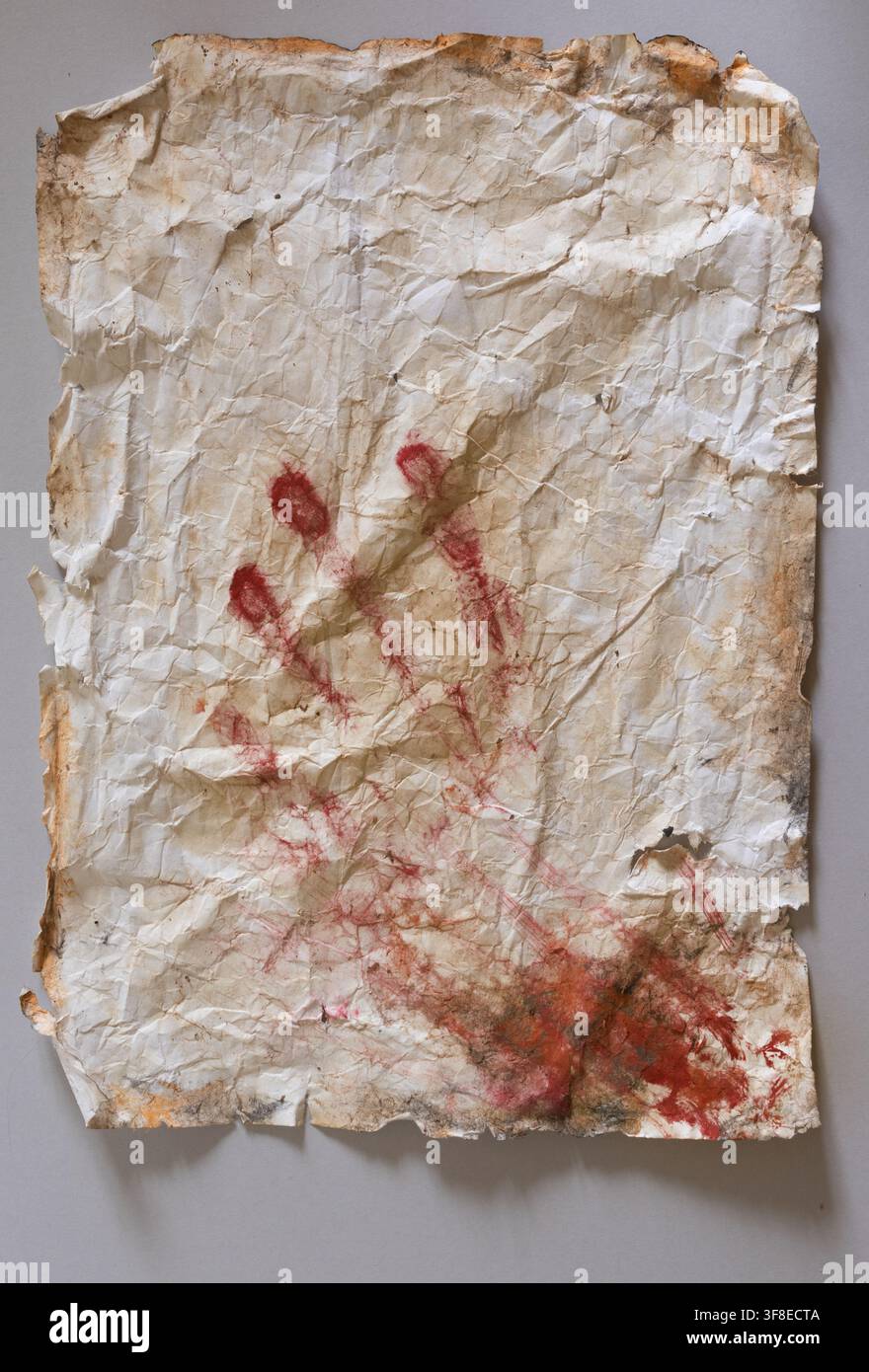 Gealtertes Papier mit rotem Handabdruck — Historische und künstlerische Textur auf grauem Hintergrund Stockfoto