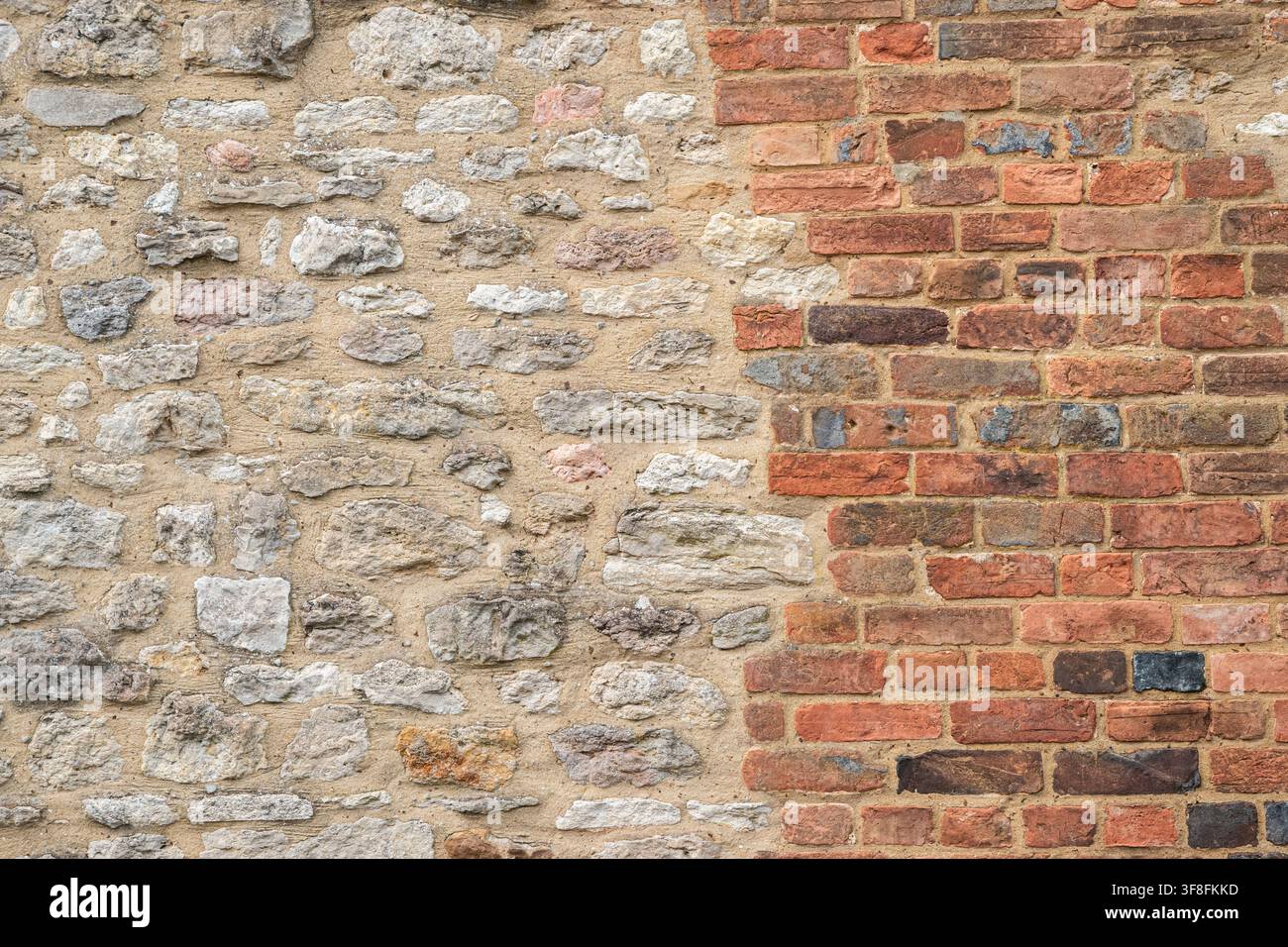 Traditionelle alte Mauer aus unregelmäßigem Naturstein und verwittertem roten Ziegelmauerwerk. Stockfoto