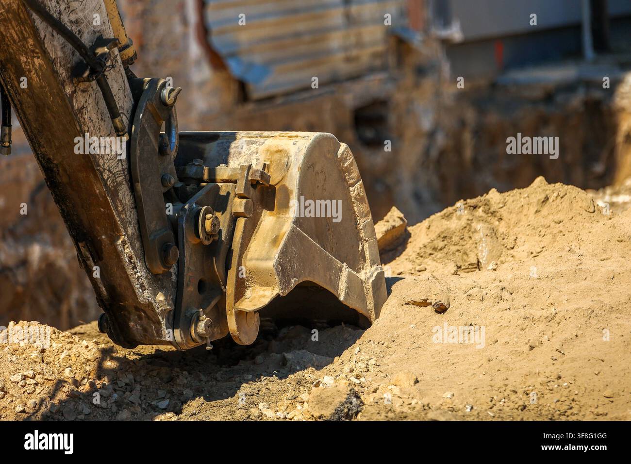Baggerlöffel gräbt Erde während Erdarbeiten auf einer aktiven Baustelle Stockfoto