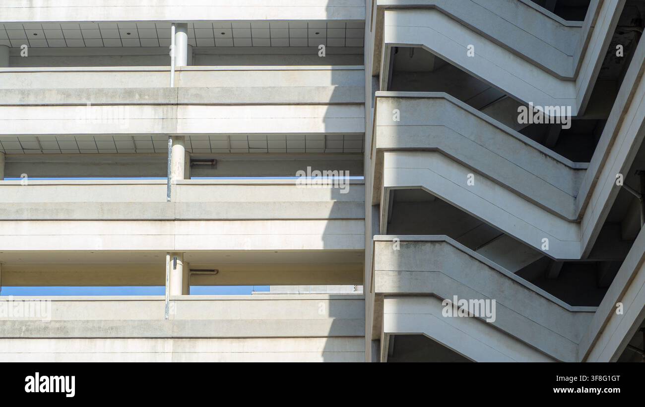 Betongebäudefassade mit Feuerleiter, minimalistische Architekturstruktur, geometrisches Wanddesign mit Schatten, urbaner Immobilienentwicklungsbau Stockfoto